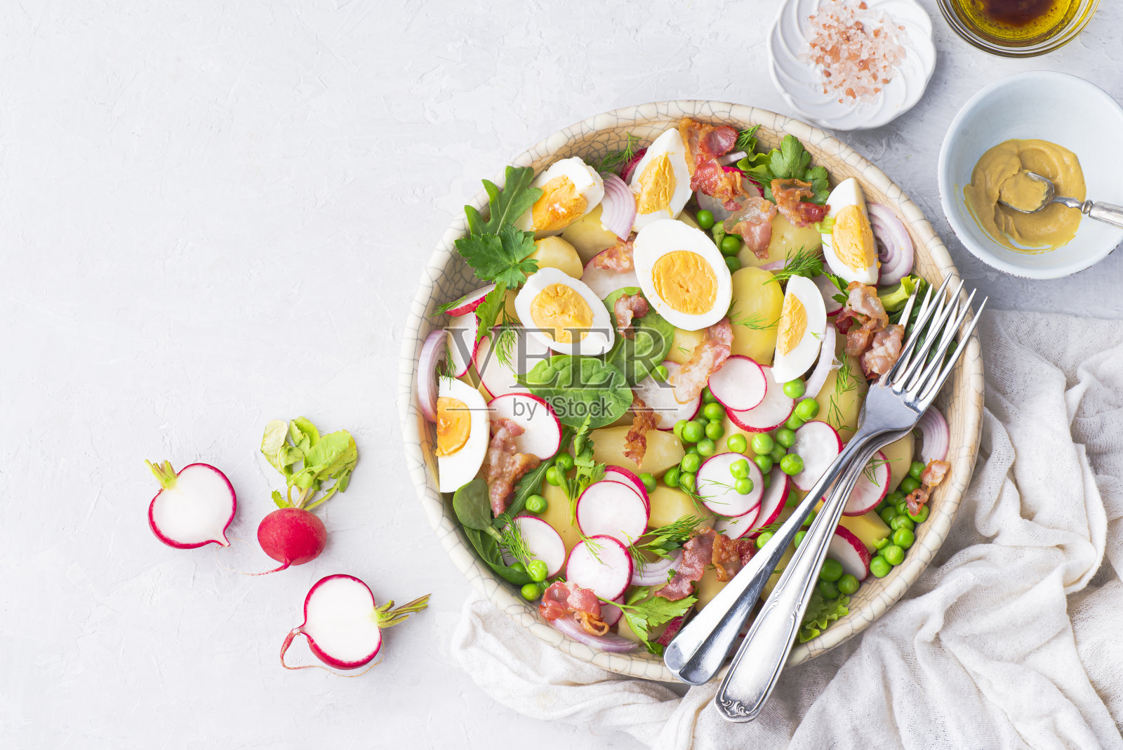 夏季快速均衡的沙拉，有小土豆、炸培根、萝卜、农民有机鸡蛋、绿豌豆和香草，用橄榄油、芥末酱、香醋和柠檬调味。春天均衡饮食，干净健康午餐照片摄影图片