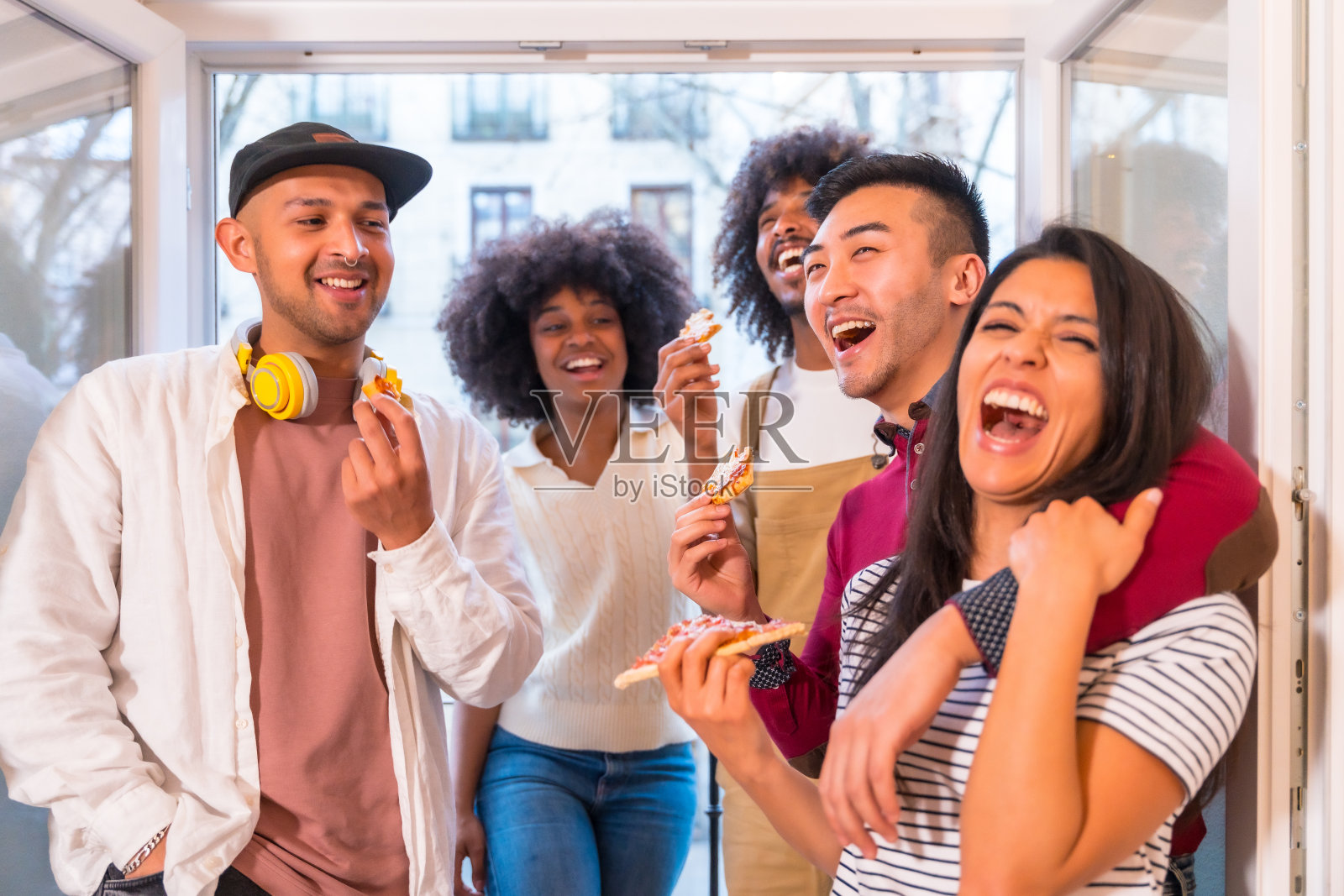 一群朋友在家里的露台上吃着披萨，谈笑风生，午餐或晚餐，生活方式照片摄影图片
