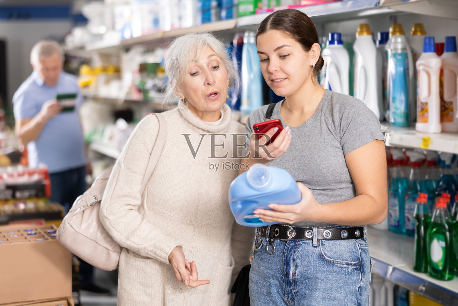 小女孩和老妇人在商店里扫描洗衣粉上的二维码照片摄影图片