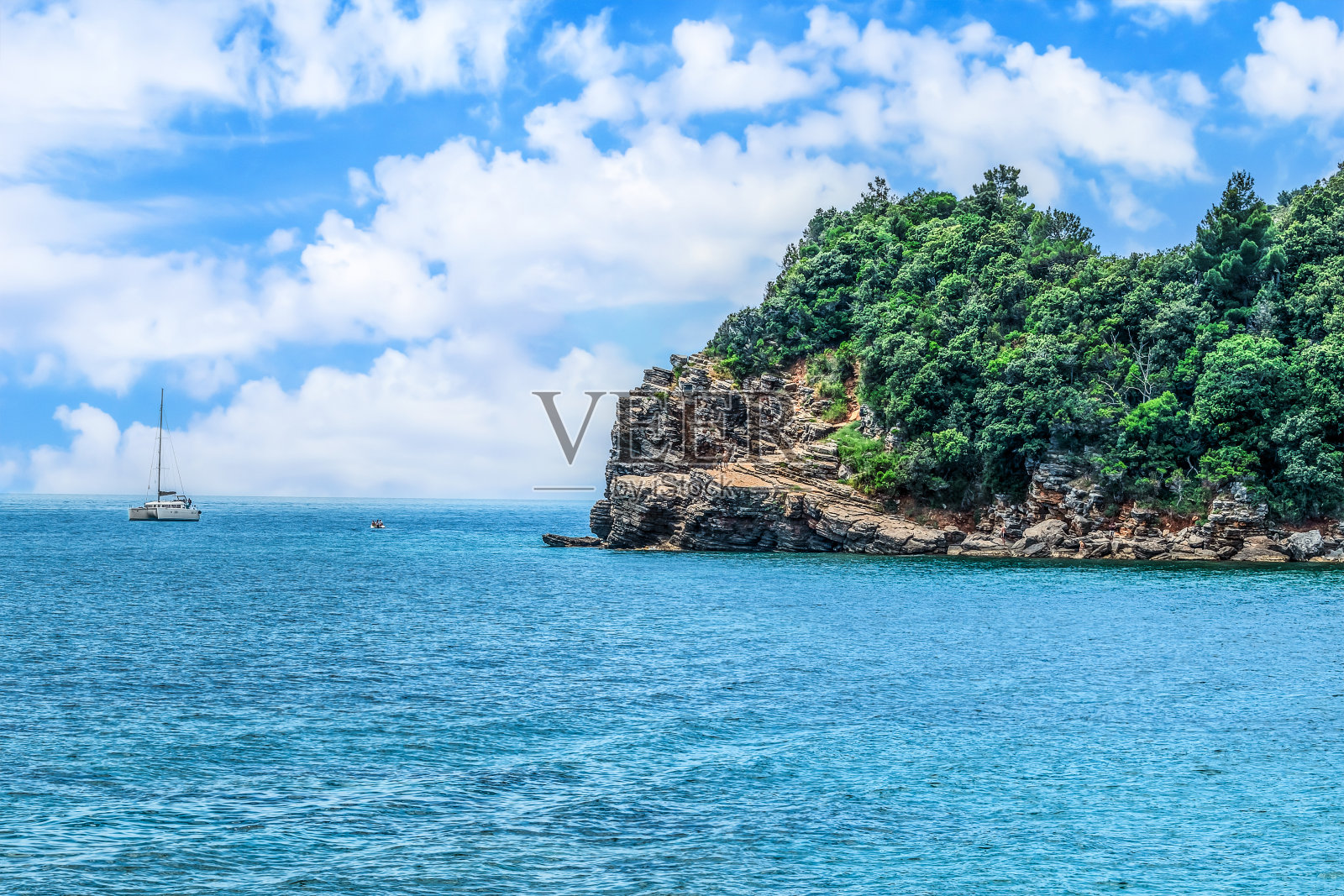 游艇航行在亚得里亚海经过一个分层的石头悬崖，从莫格伦海滩在布德瓦，黑山照片摄影图片