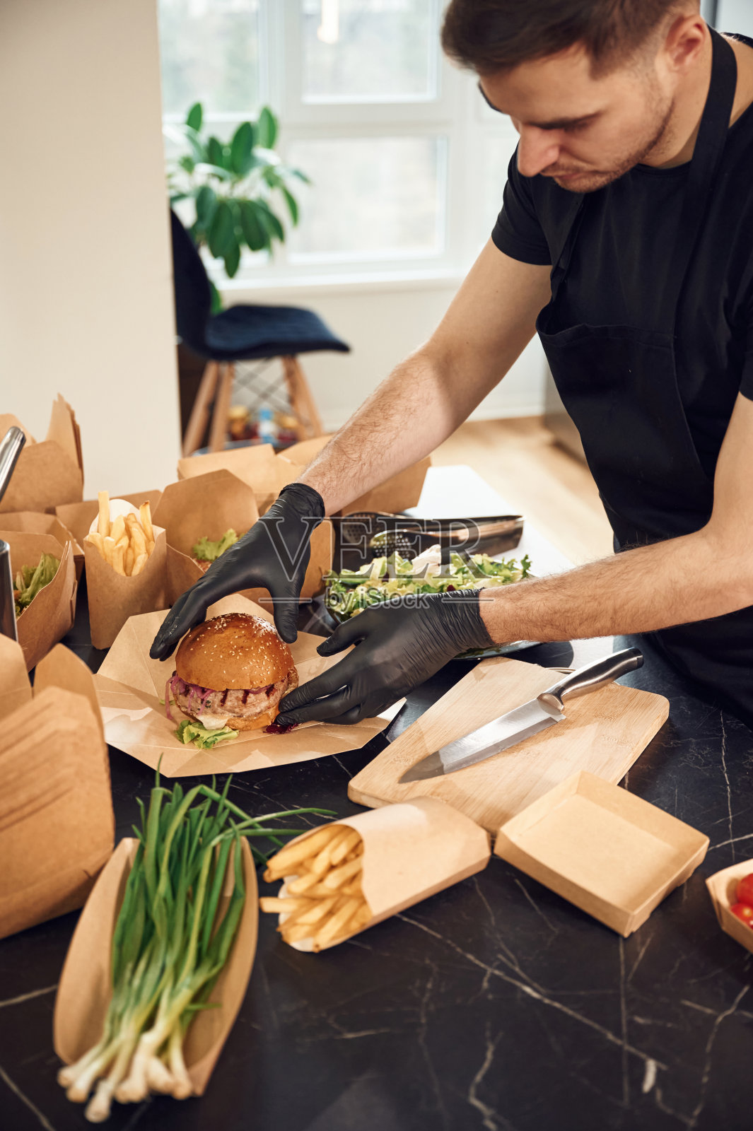 汉堡在手。一个人正在把食物装进环保纸盒里。在室内,餐厅照片摄影图片