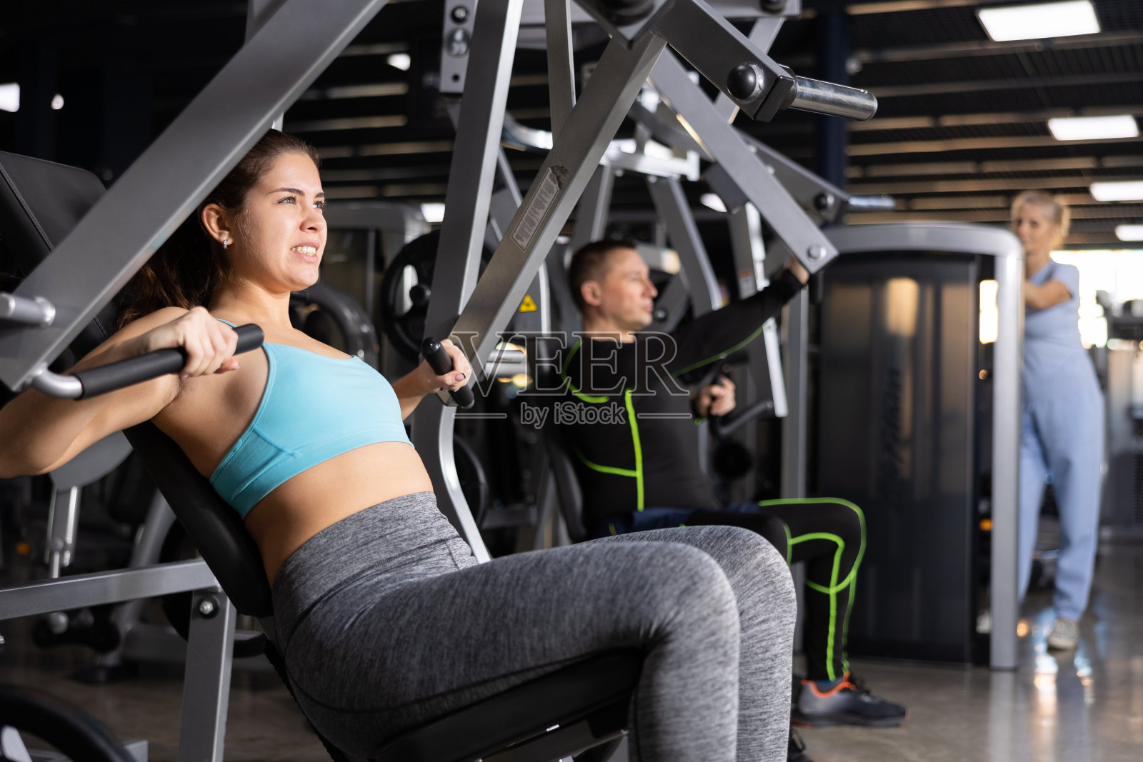 年轻女孩在健身房的运动机器上进行胸部按压照片摄影图片