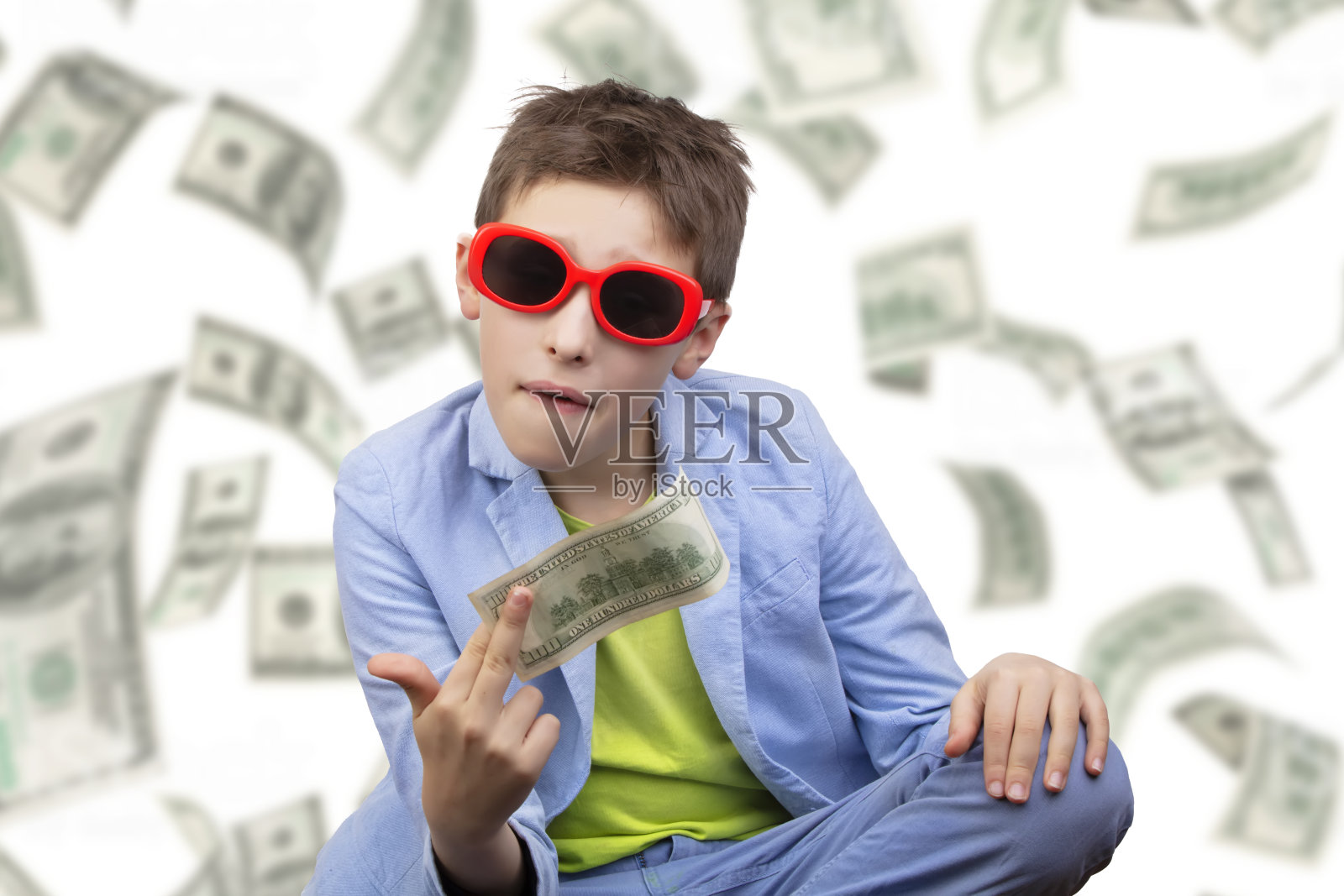 一个可爱的富家子弟，戴着眼镜，手里拿着美元，知道如何在钞票掉落的背景下赚钱。照片摄影图片