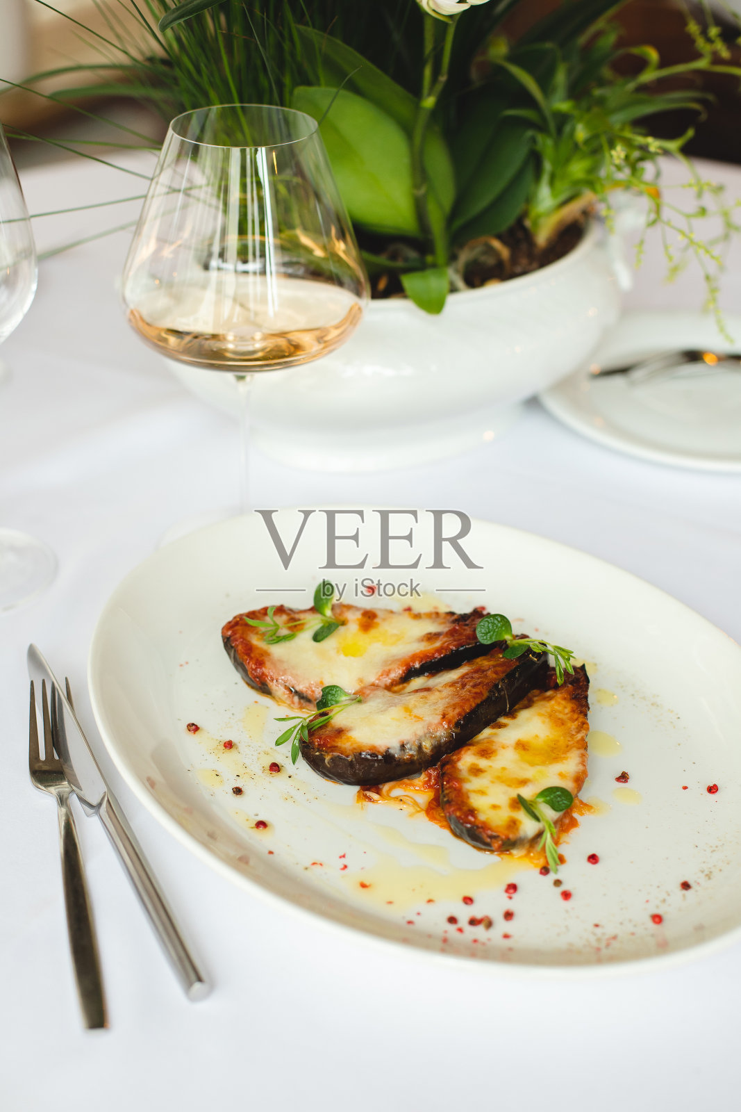 用白色大盘子烤蔬菜。在明亮的背景下，一杯玫瑰色葡萄酒。照片摄影图片