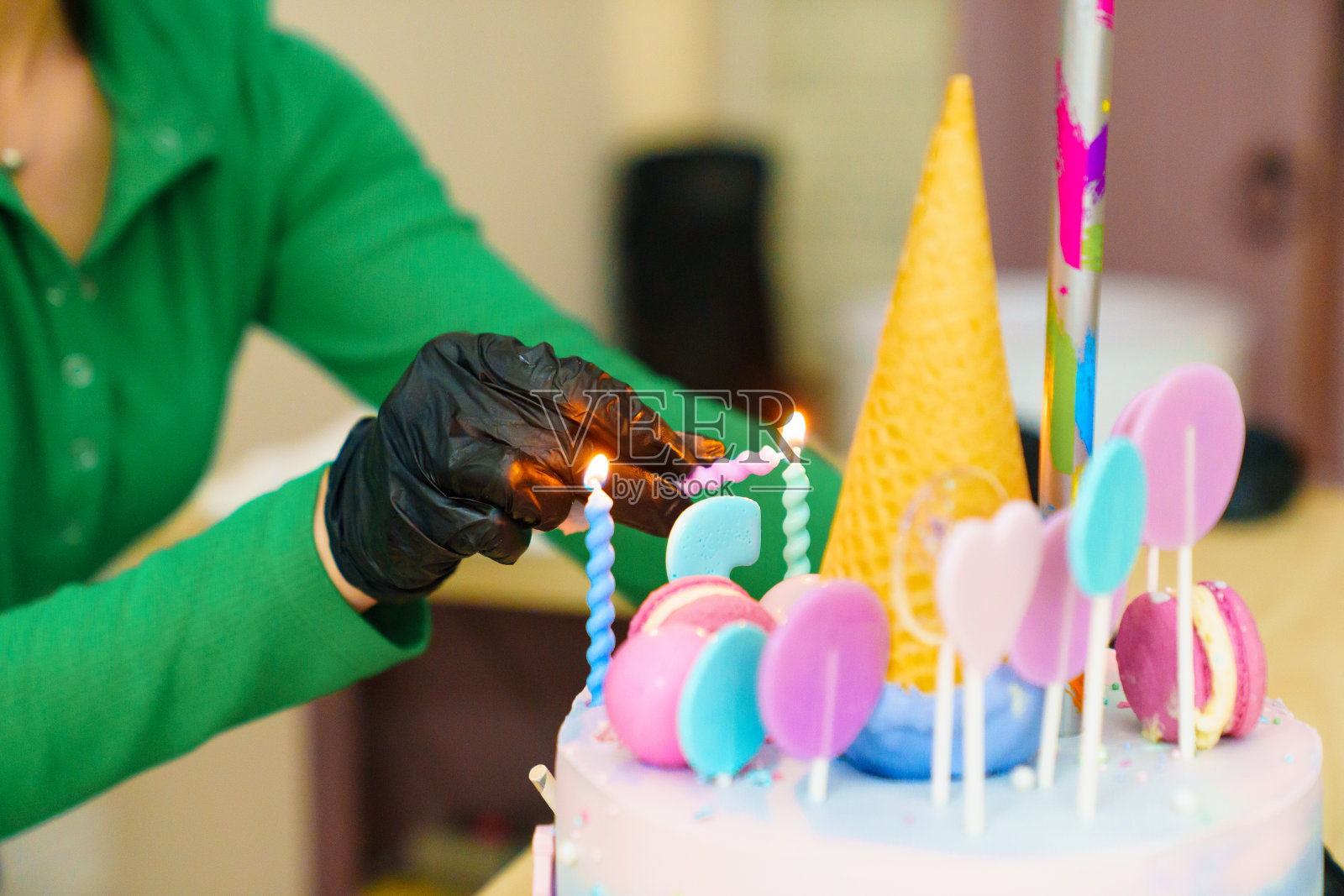 一名戴着黑色手套的妇女在蛋糕上点燃蜡烛。照片摄影图片
