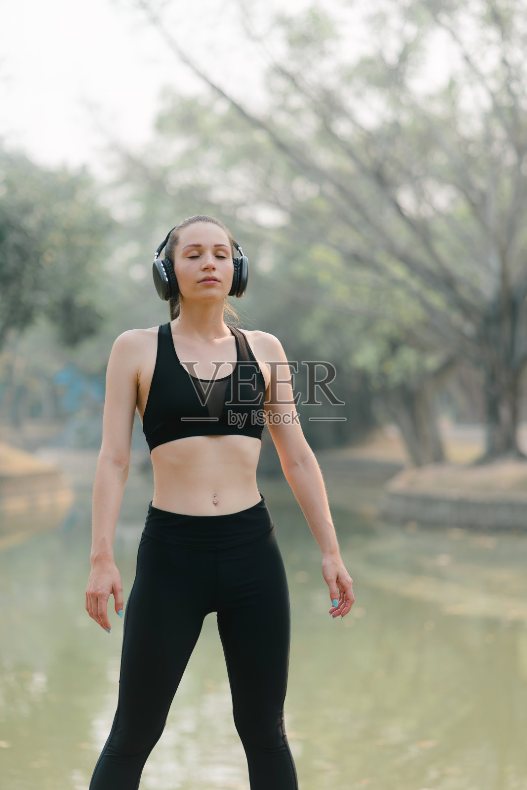 一位美丽迷人的亚洲女子在秋日城市公园的背景下练习莲花姿势。照片摄影图片