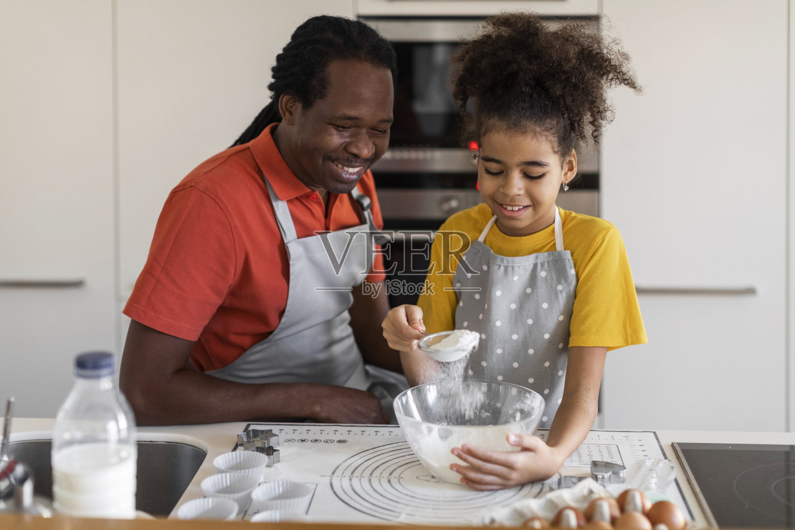 快乐的黑人家庭父亲和未成年女儿在厨房烘焙照片摄影图片