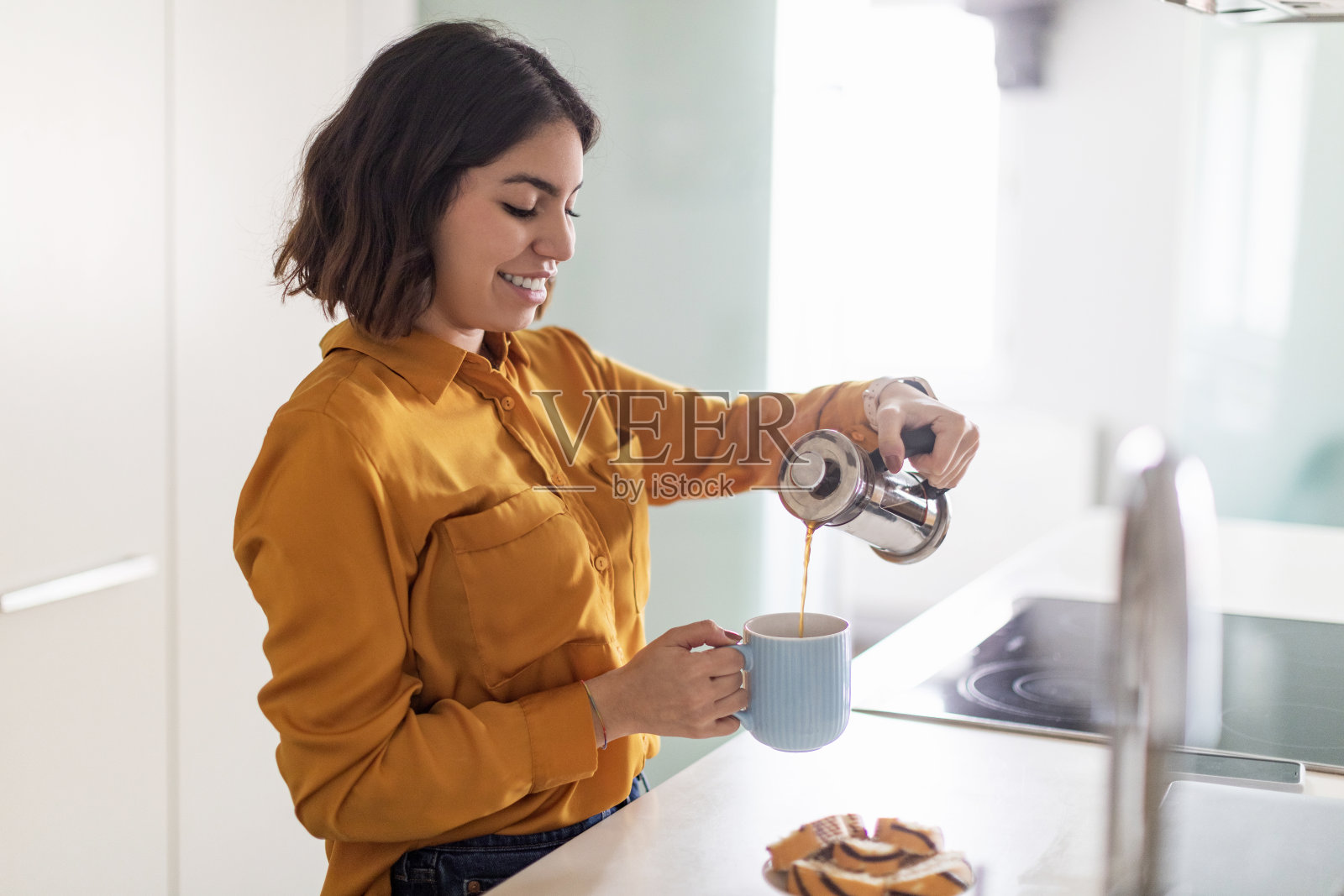 年轻漂亮的阿拉伯女人从现代厨房的法式压滤机倒咖啡照片摄影图片