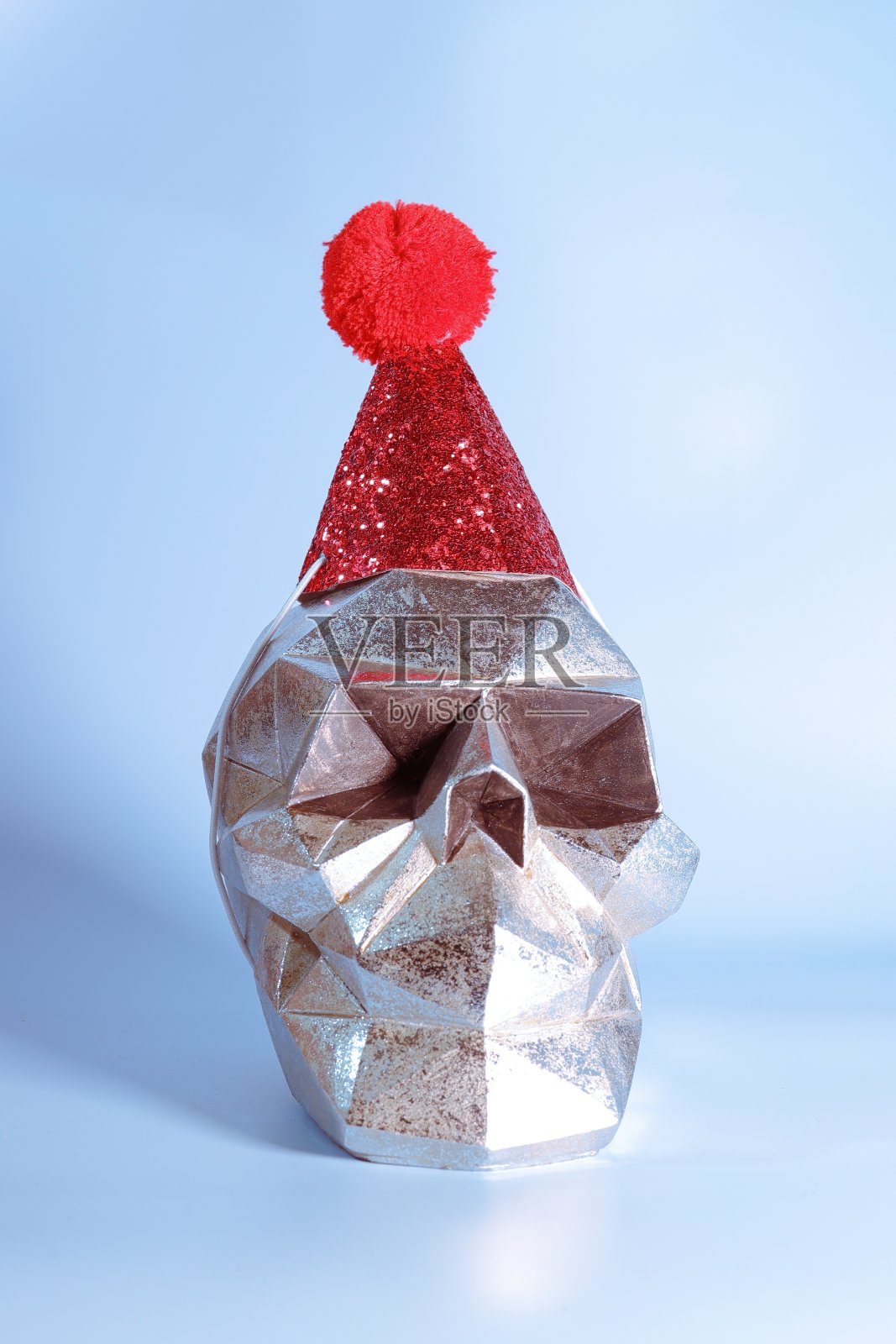 银色骷髅头戴着红色闪闪发光的生日帽照片摄影图片