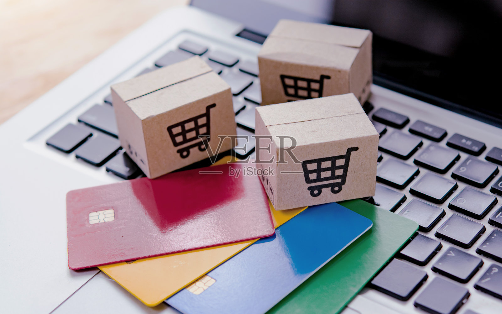 网上购物。信用卡和笔记本电脑键盘上有购物车标志的纸板箱。网上购物服务。提供送货上门服务照片摄影图片