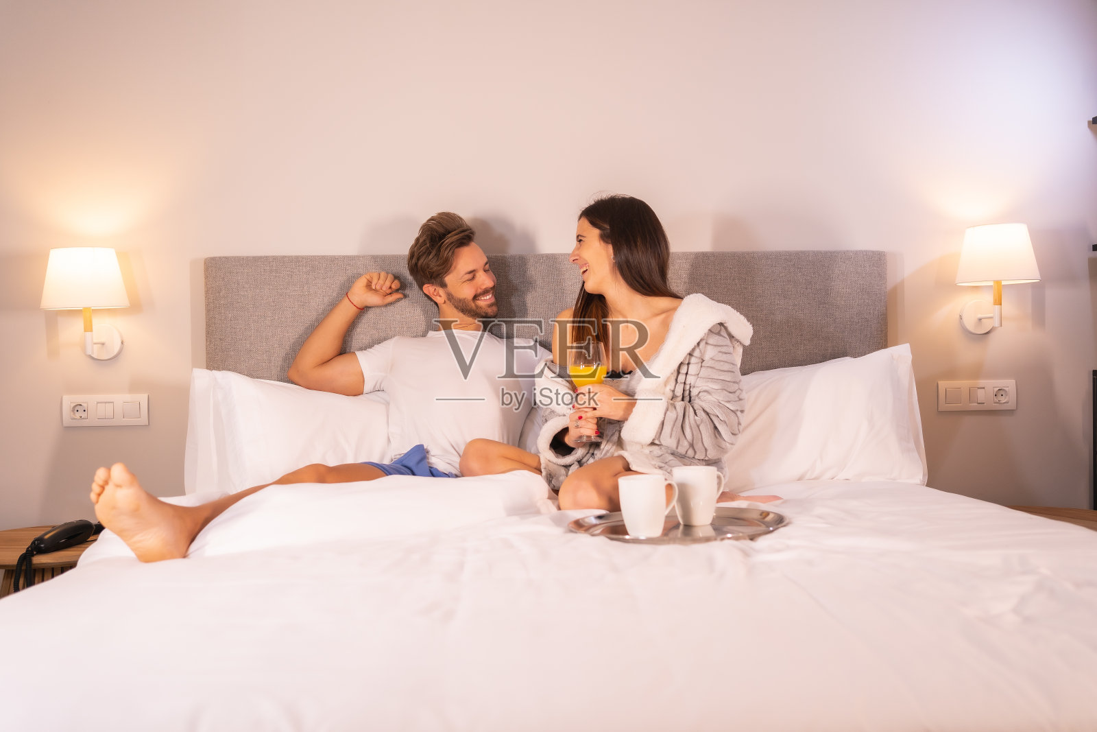 刚醒来的白人夫妇在酒店房间的床上喝果汁和咖啡作为早餐照片摄影图片
