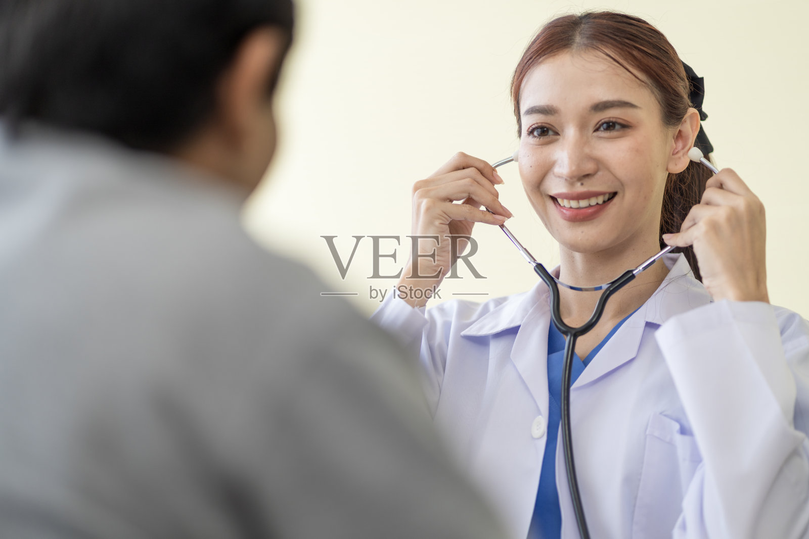 图为，亚裔医生在医院微笑着与患者交谈，鼓励患者照片摄影图片