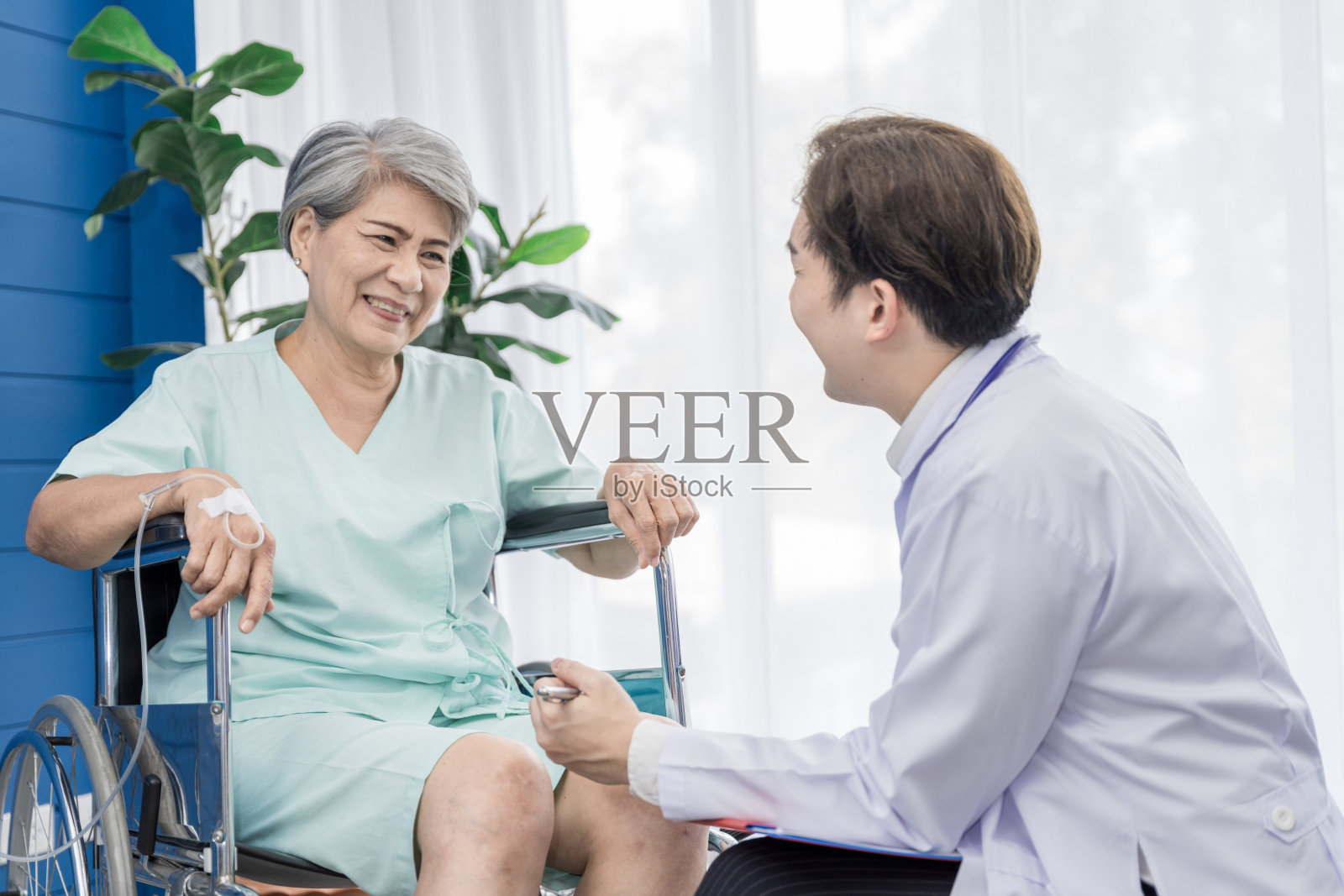 在接受膝盖手术的某医院，一位医生正在照顾一位上了年纪的女患者。这使得她需要使用轮椅而不是走路，并有医生密切照顾。照片摄影图片