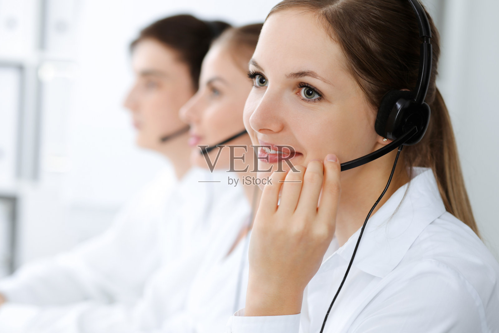 呼叫中心。美丽的年轻女子使用耳机和电脑来帮助客户。经营理念照片摄影图片