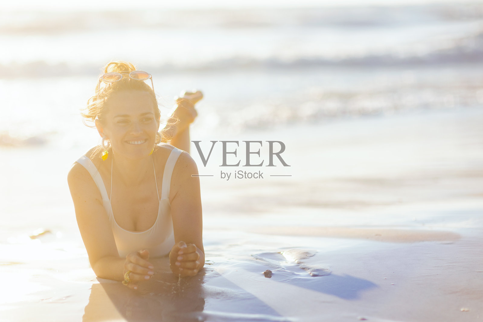 快乐的优雅女子在白色泳装躺在海滩照片摄影图片