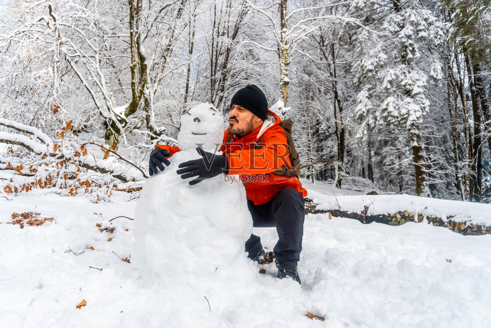 一位有趣的徒步旅行者在西班牙阿蒂库扎自然公园的雪林里和一个雪人开玩笑照片摄影图片
