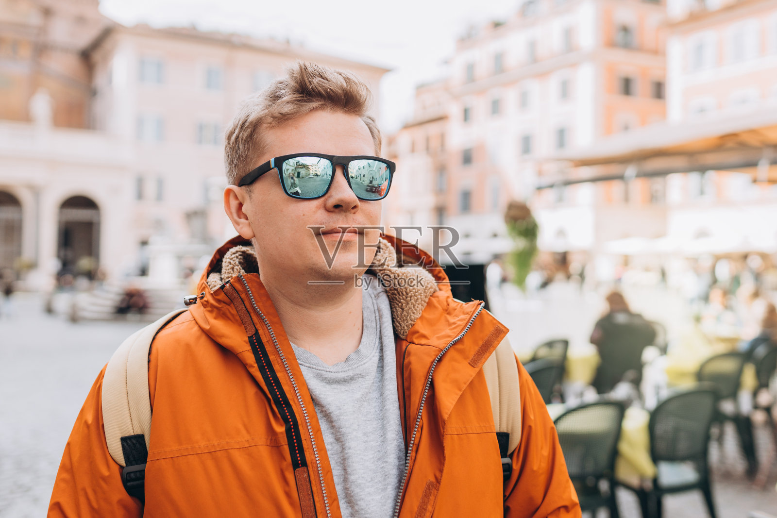 一个帅哥在城市里穿行的短镜头。戴着墨镜背着黄色背包的年轻人走在城市街道上照片摄影图片