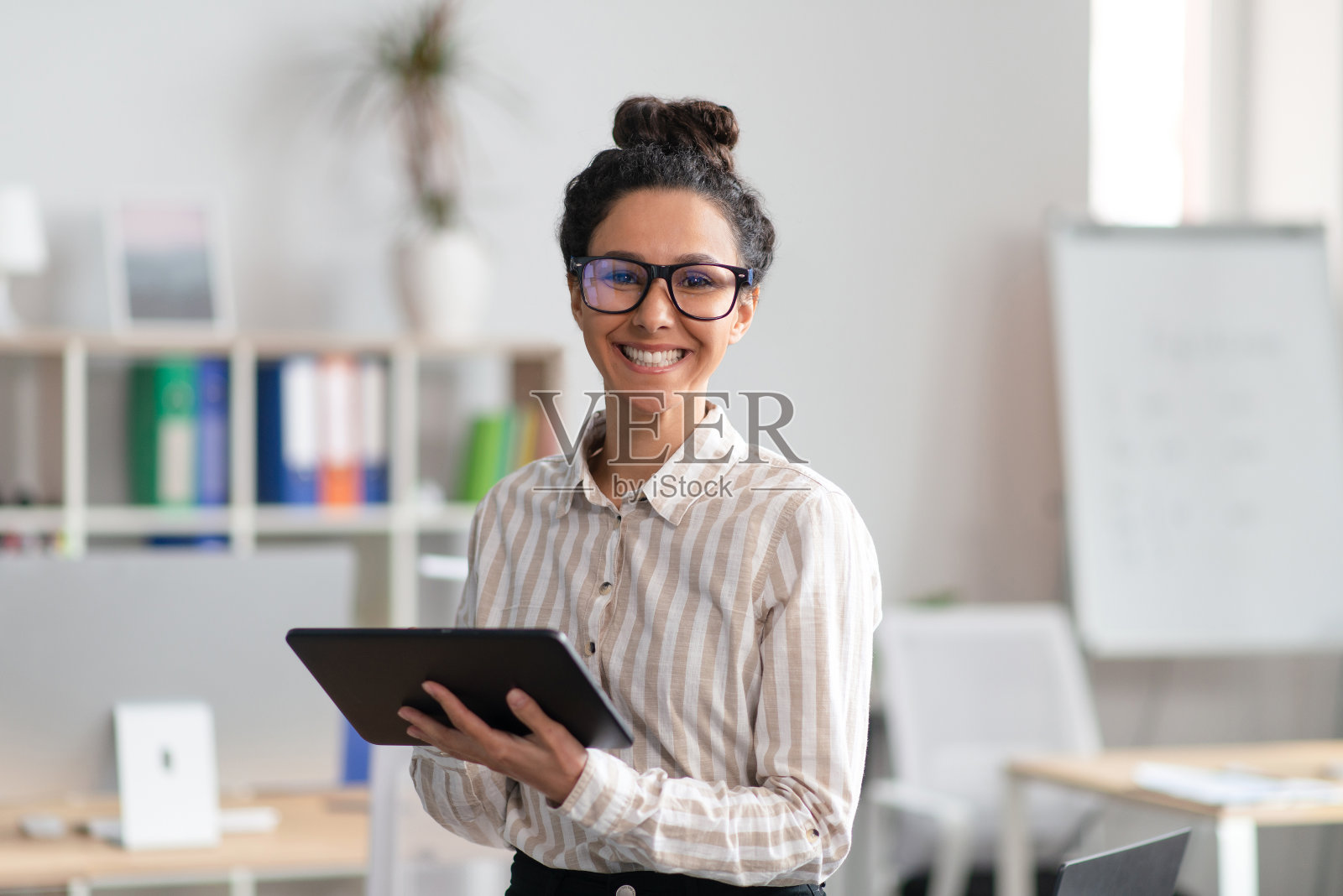 快乐的年轻女创业者手持平板电脑，在商务办公室使用现代技术照片摄影图片