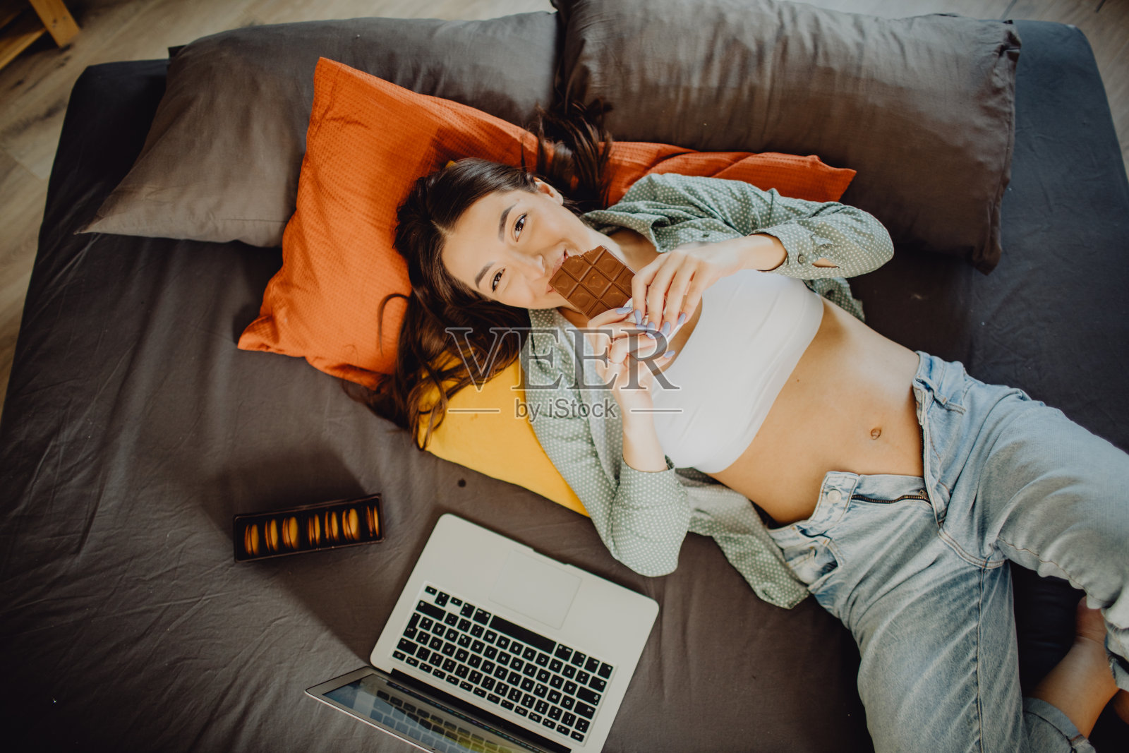 一名年轻孕妇在床上放松时吃巧克力的俯视图肖像照片摄影图片