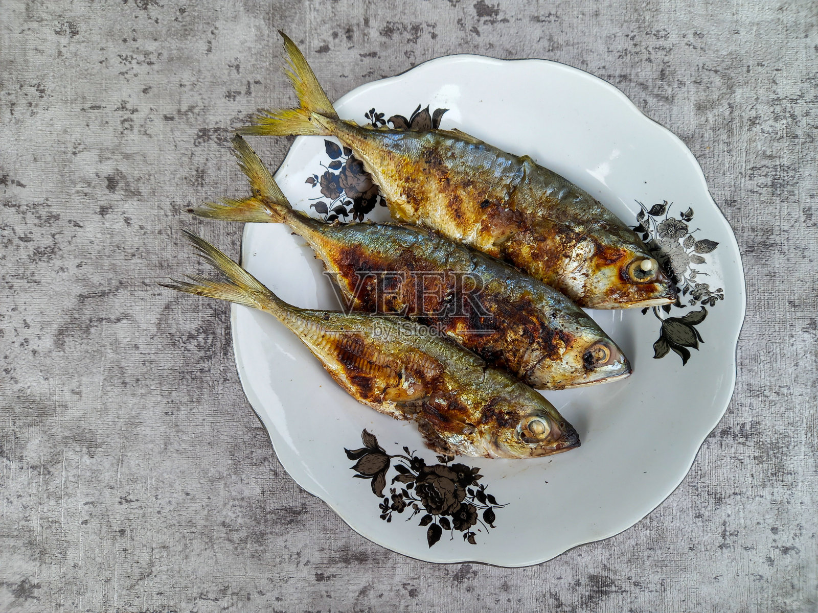 Ikan kembung bakar，白盘子烤鲭鱼。鲭鱼是印度尼西亚水域的一种鱼类。海洋食品。印尼的食物。照片摄影图片