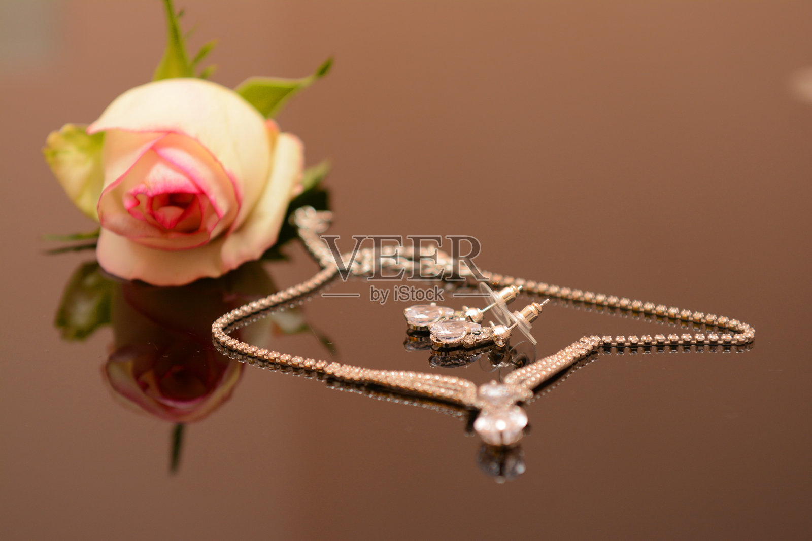 米色玫瑰和黄金项链放在桌子上作为背景，有tex的空间照片摄影图片