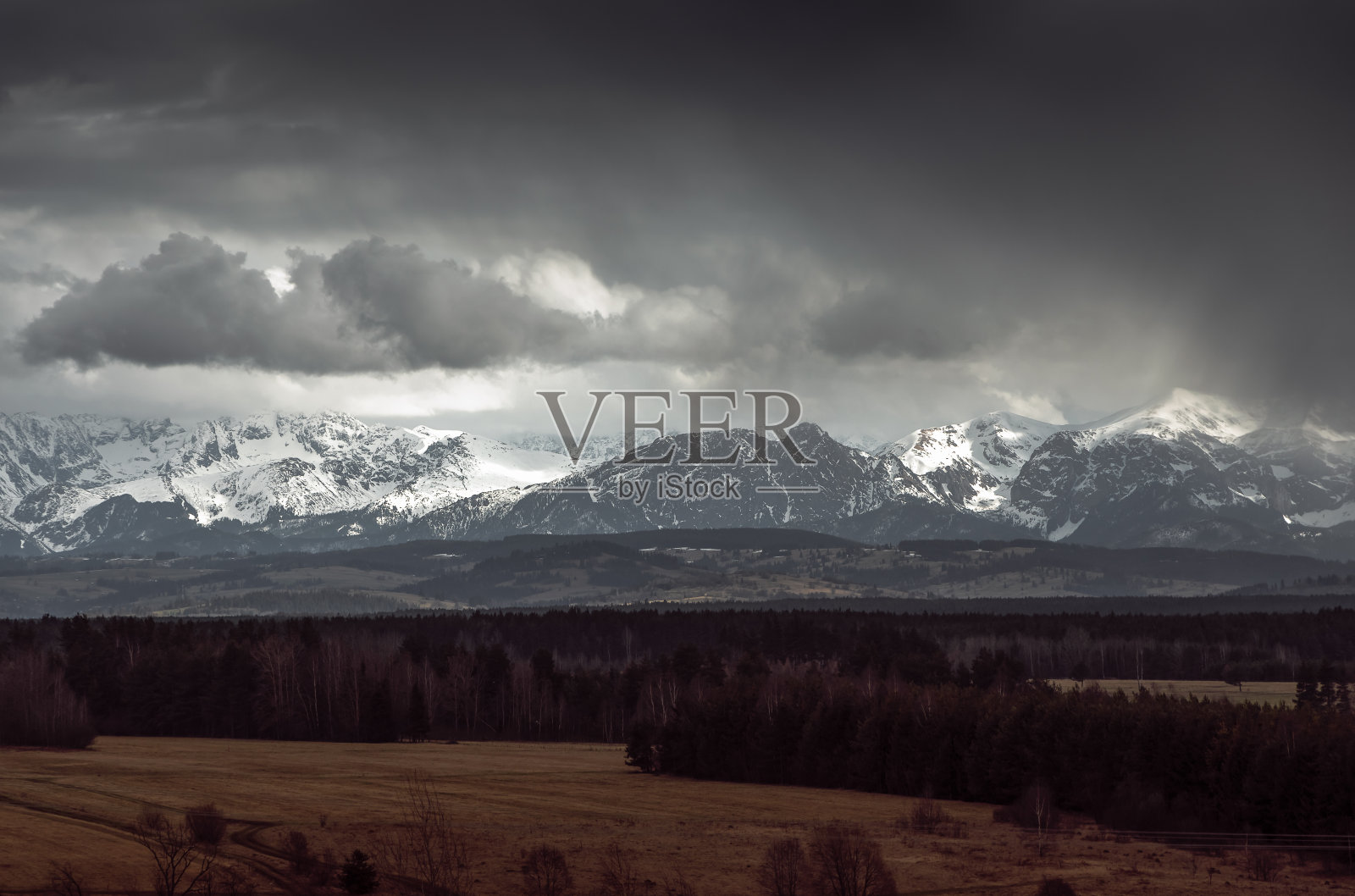 明亮的山被乌云包围，即将下雨。戏剧性的天空。山峰被白雪覆盖。西塔特拉斯，吉安特山，波兰照片摄影图片