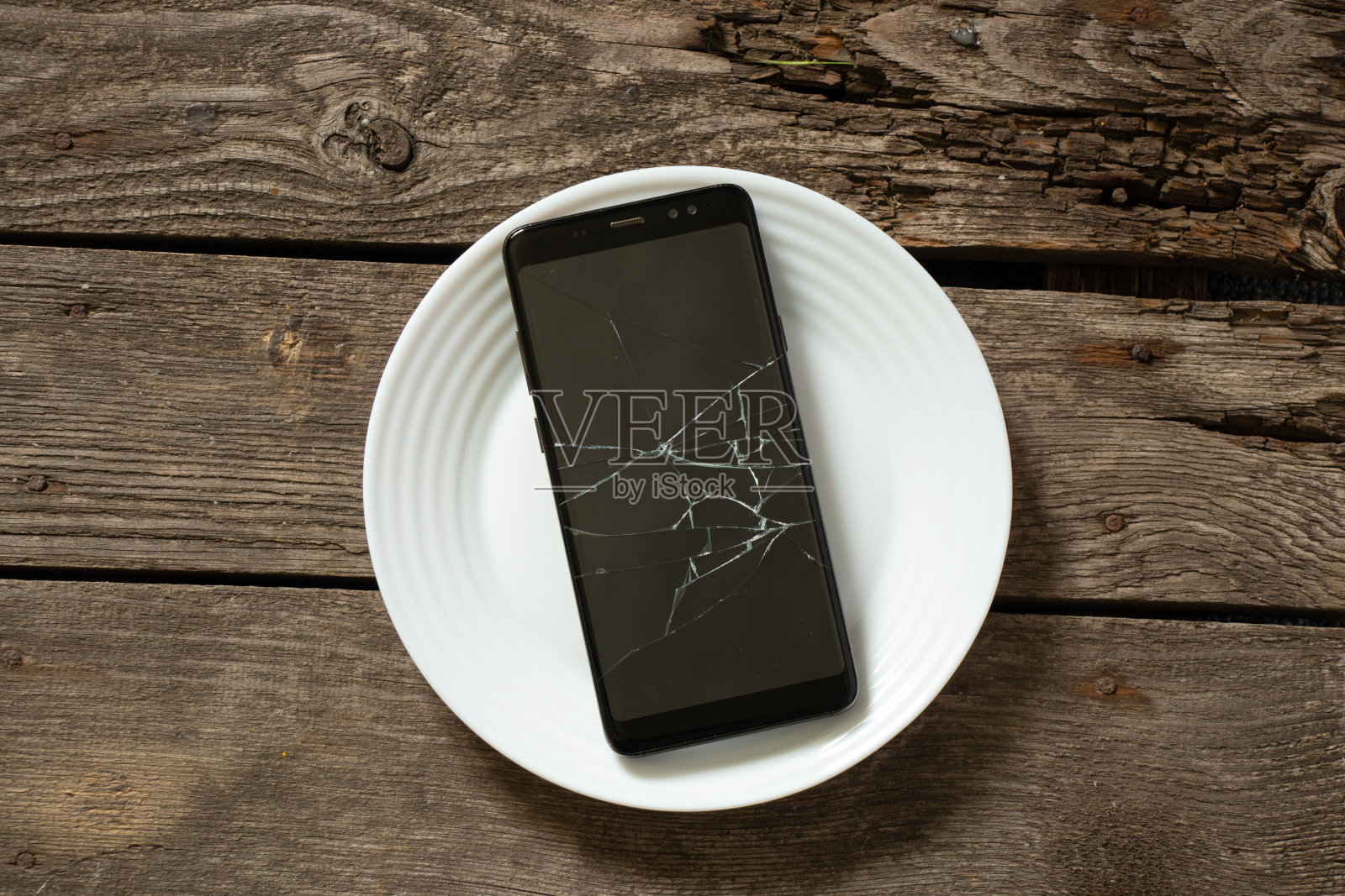 黑色手机，白色盘子上有一个破裂的屏幕特写照片摄影图片