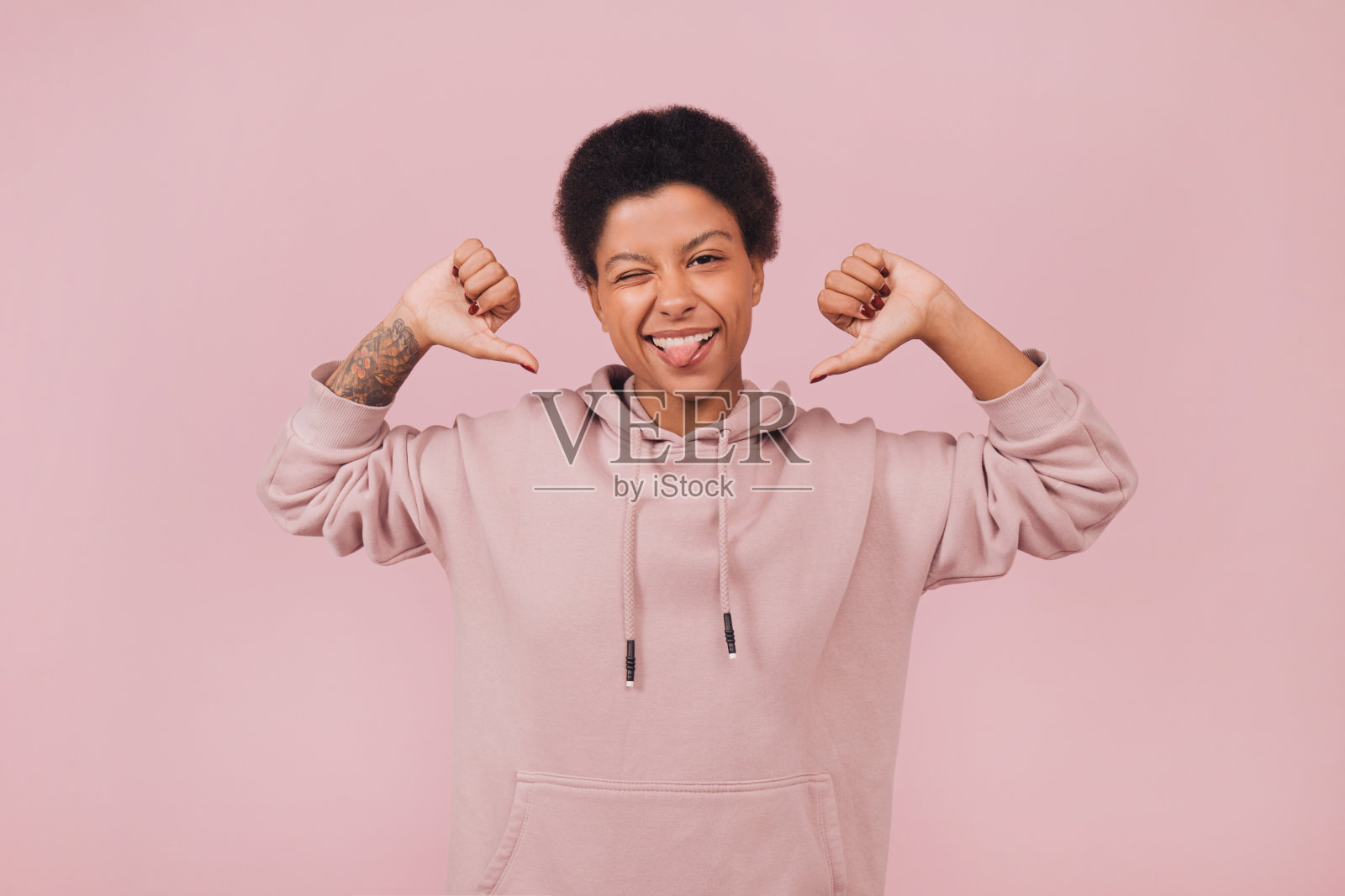 快乐的年轻黑人妇女眨眼和显示自己的大拇指。照片摄影图片