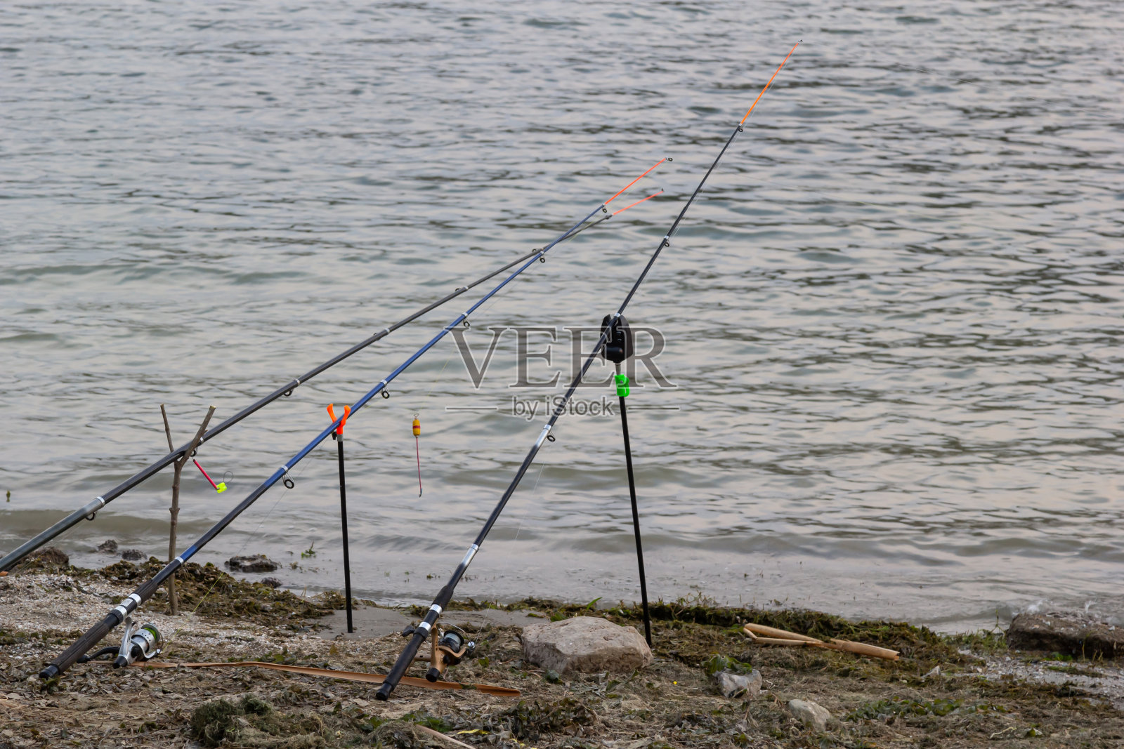 钓鱼竿和渔具放在河堤上，湖岸近距离收浪照片摄影图片