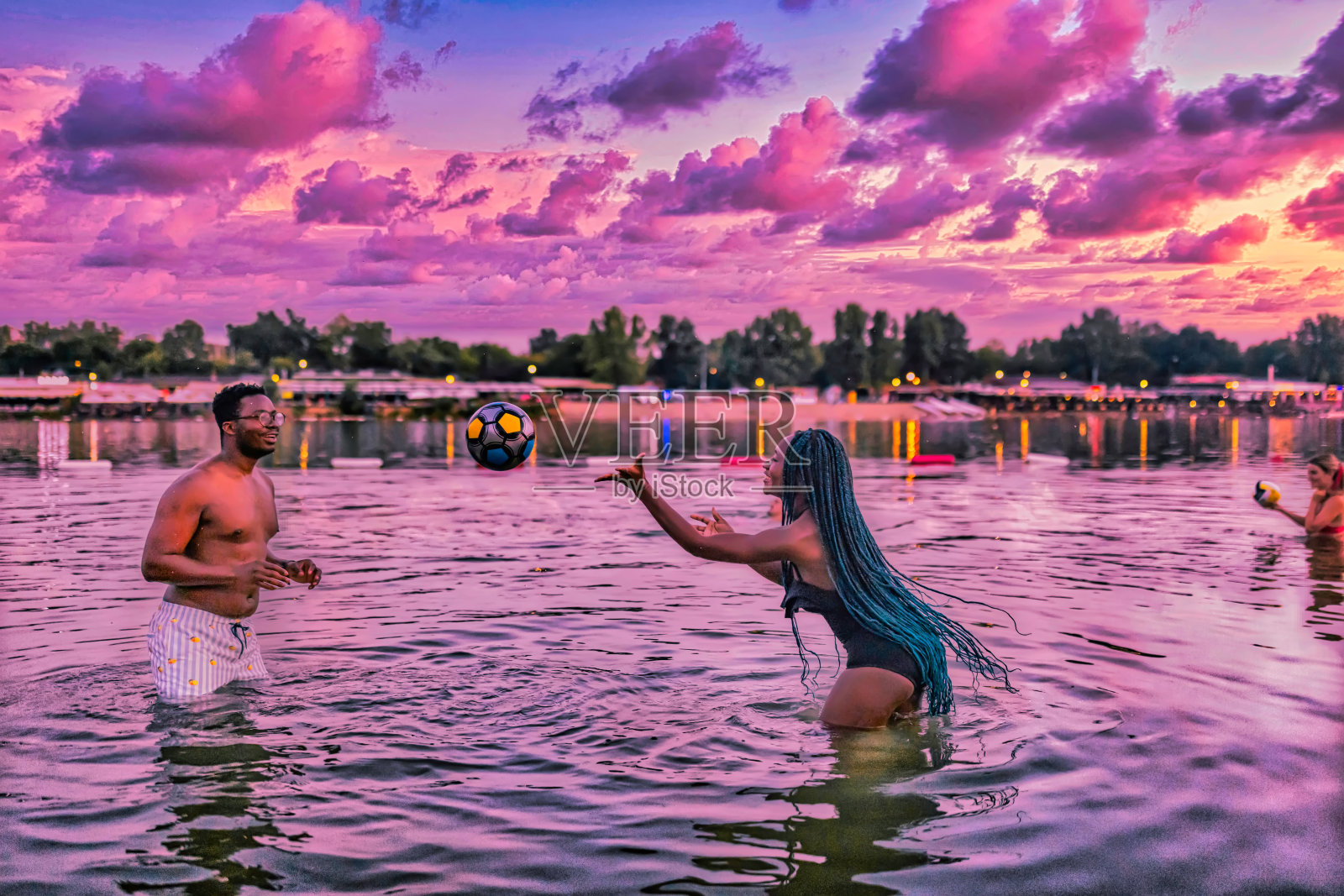 一对年轻的非洲夫妇在河里打排球的照片。照片摄影图片