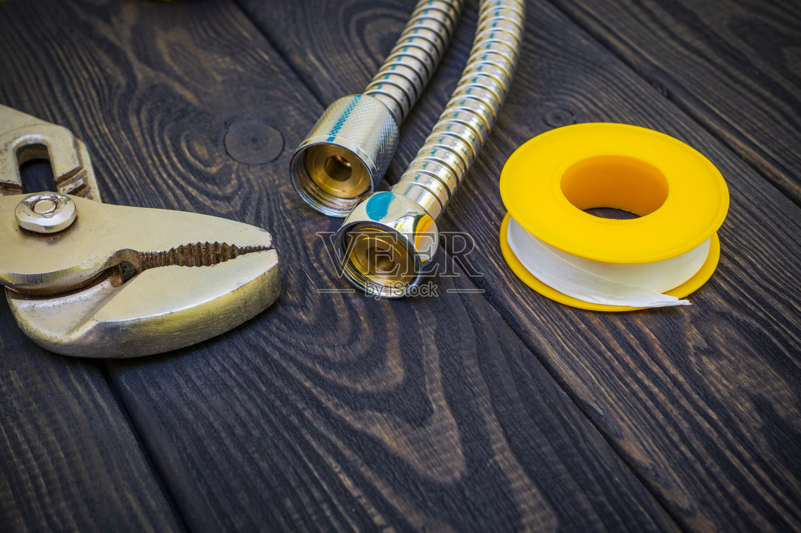 黑色木制背景上连接水管的管道工具。照片摄影图片