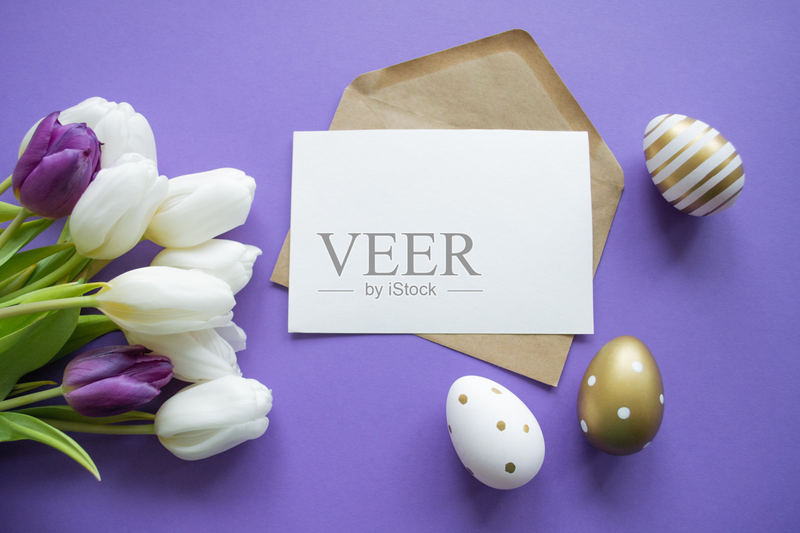 复活节祝福：紫色背景上的纸质信件，白色郁金香花束和金色图案复活节彩蛋照片摄影图片