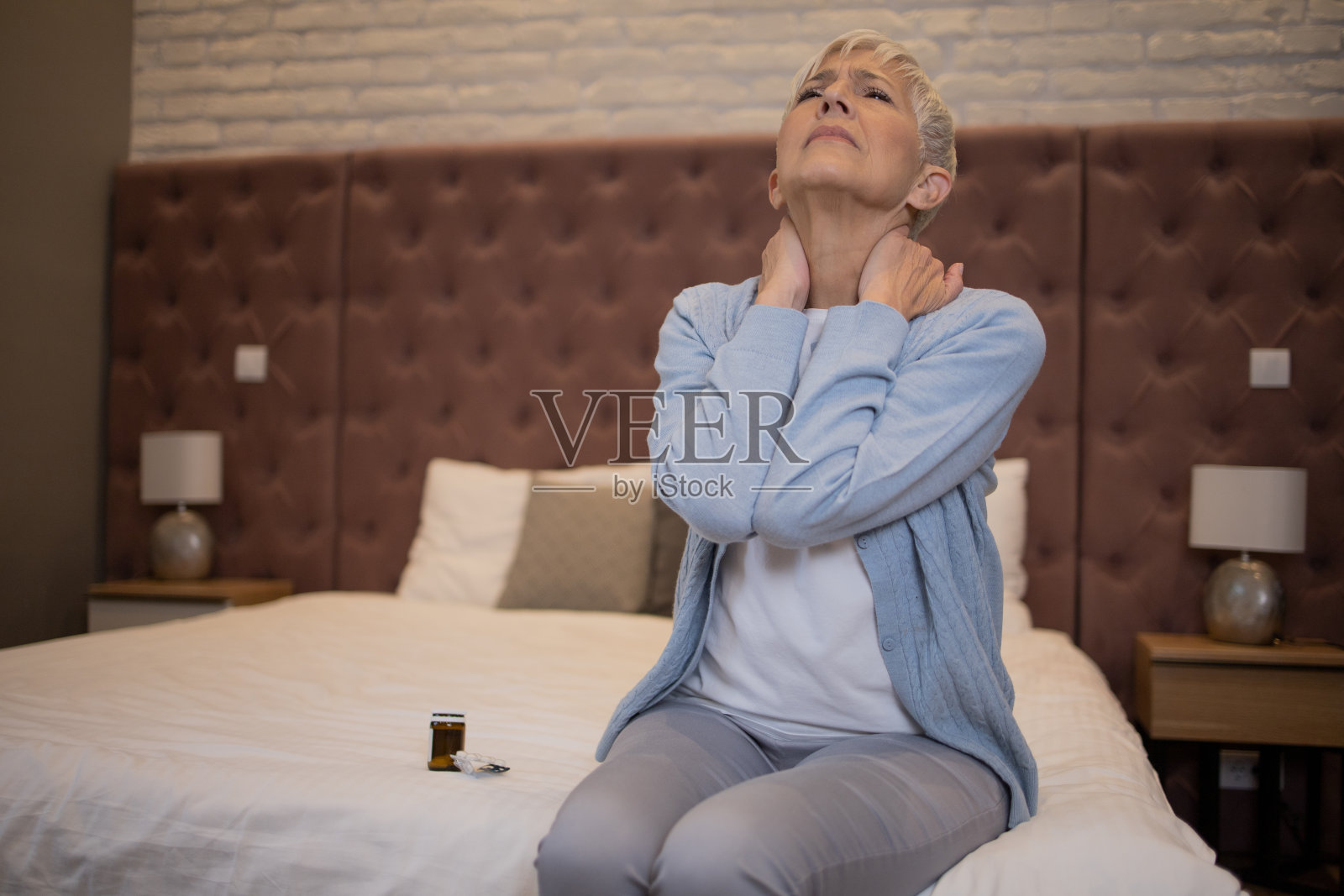 背部疼痛的老年妇女坐在沙发上照片摄影图片