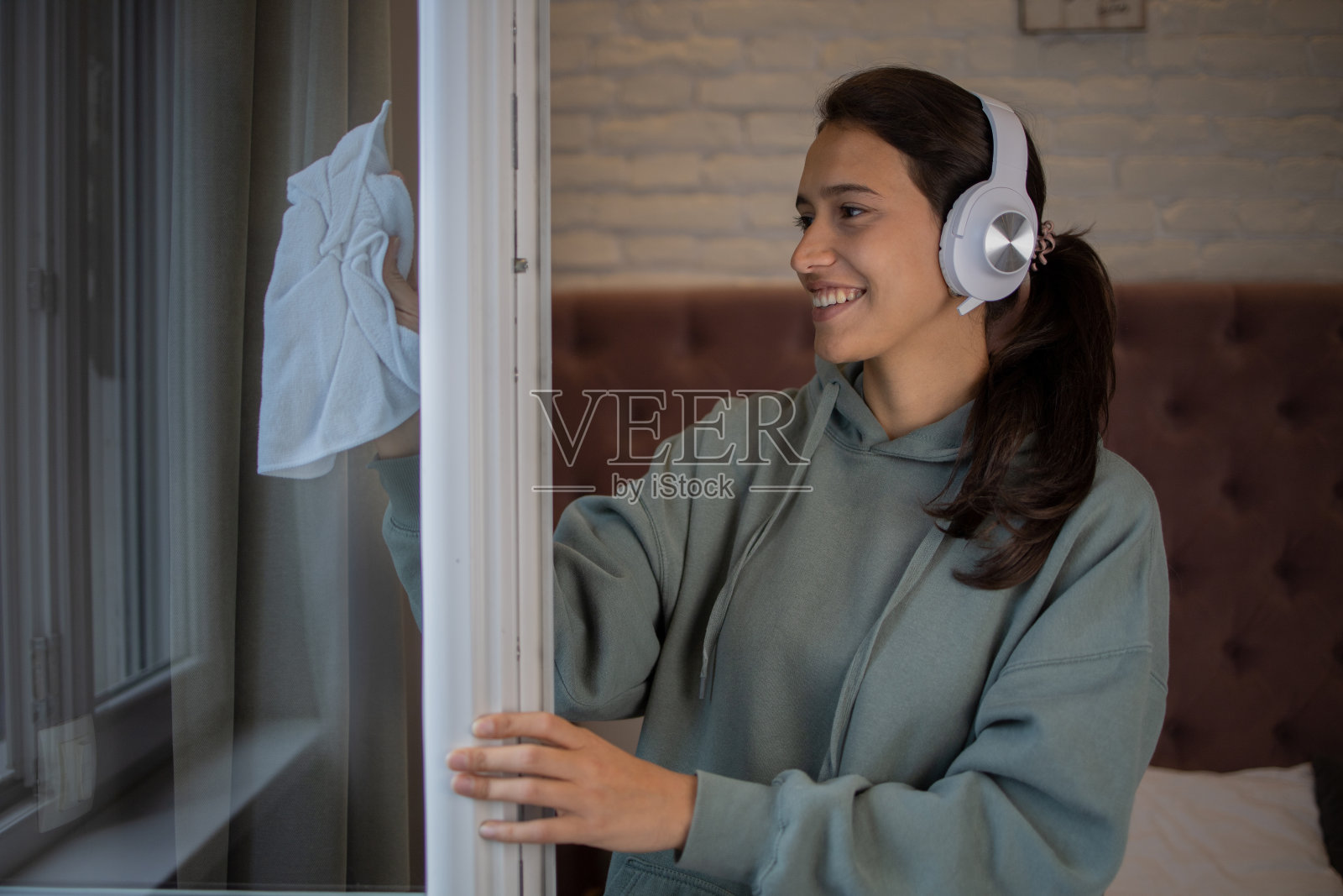 年轻女子清洁和擦拭窗户照片摄影图片