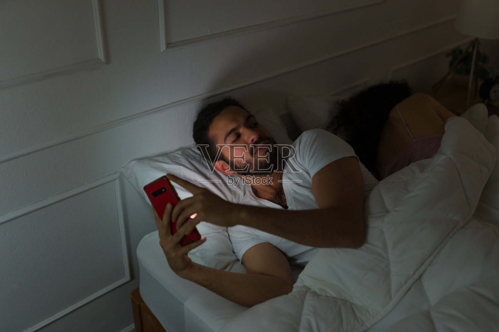 年轻男子在床上用手机玩社交媒体照片摄影图片