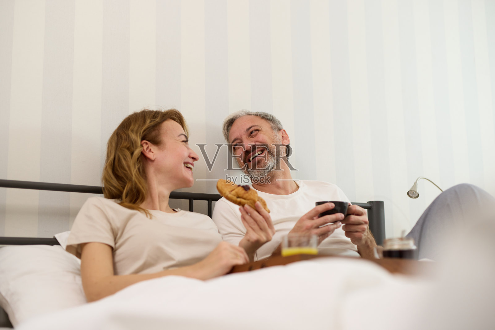 一对成熟的夫妇在家里的床上享受咖啡和早餐照片摄影图片