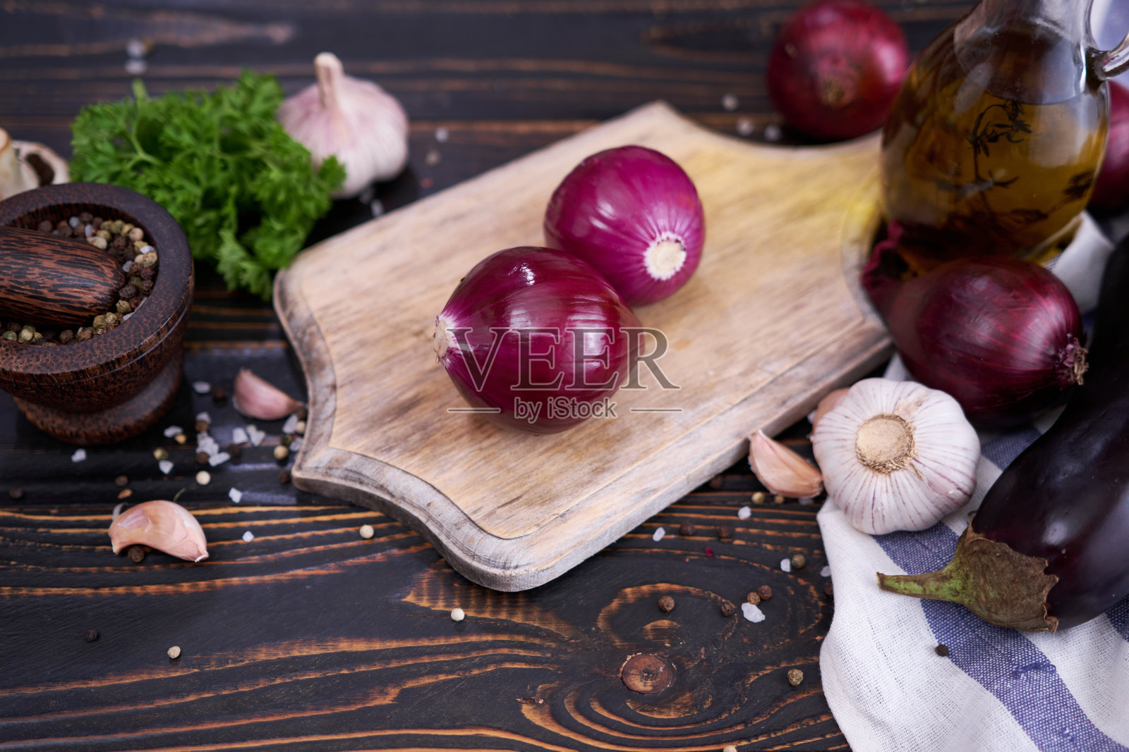 红洋葱在木砧板上，深色背景照片摄影图片