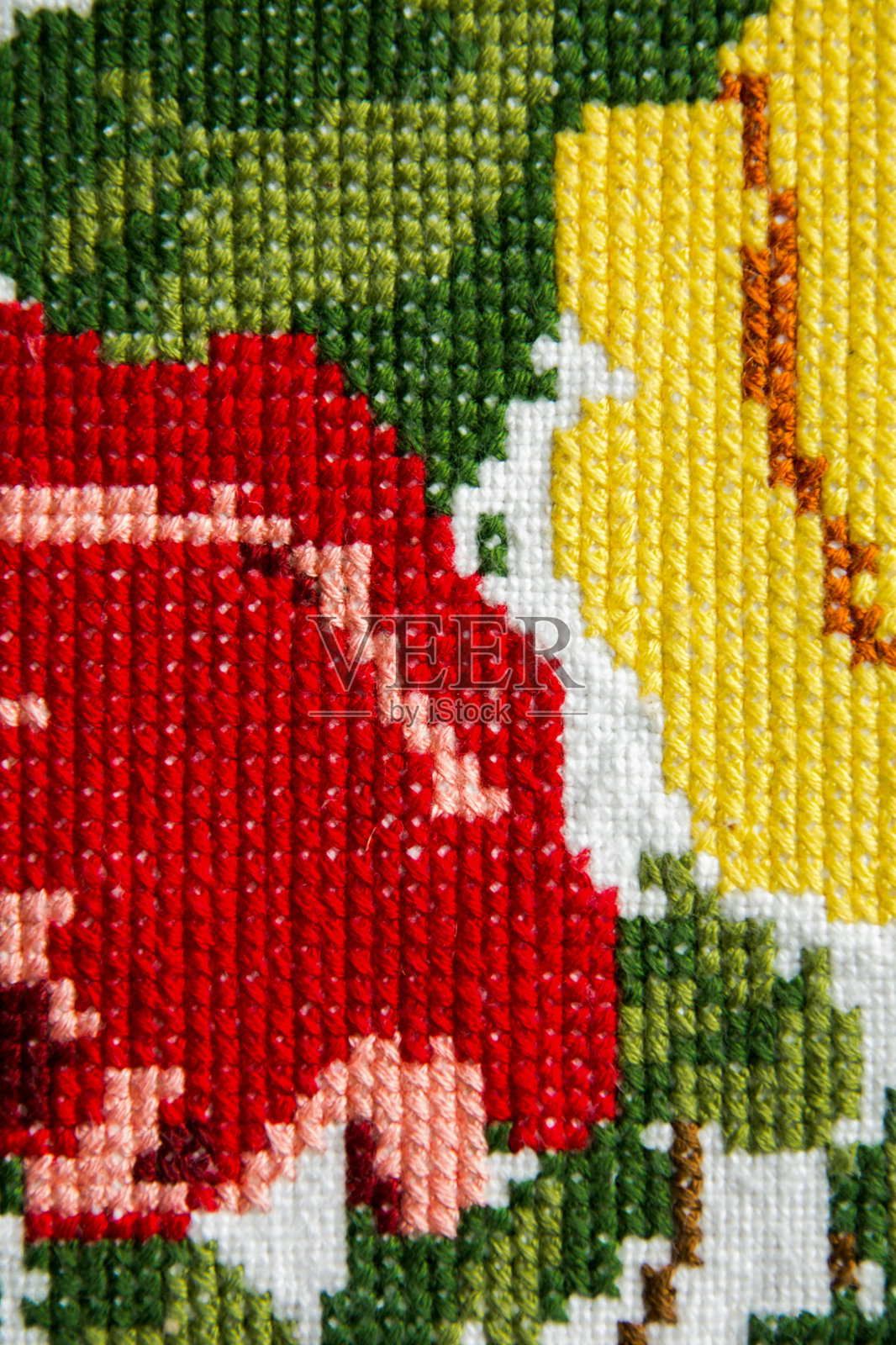 刺绣的花朵。十字绣手工。白色亚麻上有红色、黄色和淡粉色的玫瑰。照片摄影图片