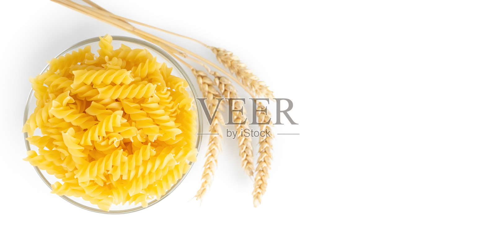 碗里的生通心粉和白色背景上的小麦小穗照片摄影图片