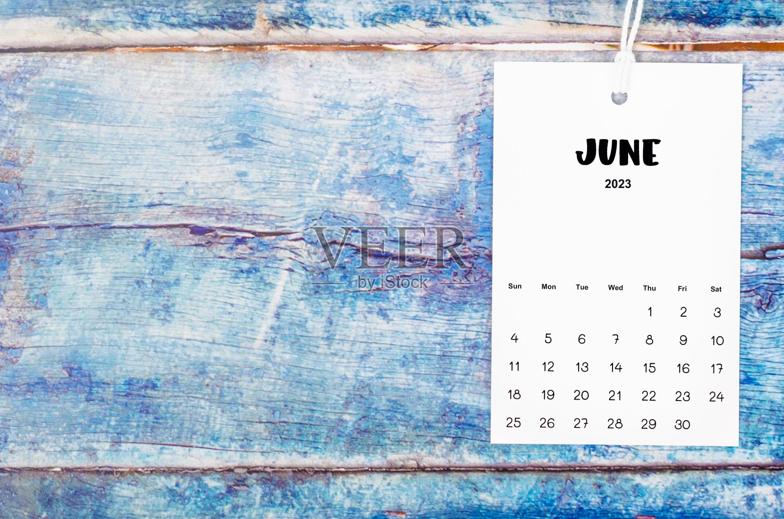 2023年6月的日历页用白绳子挂在旧的蓝色木制背景上。照片摄影图片