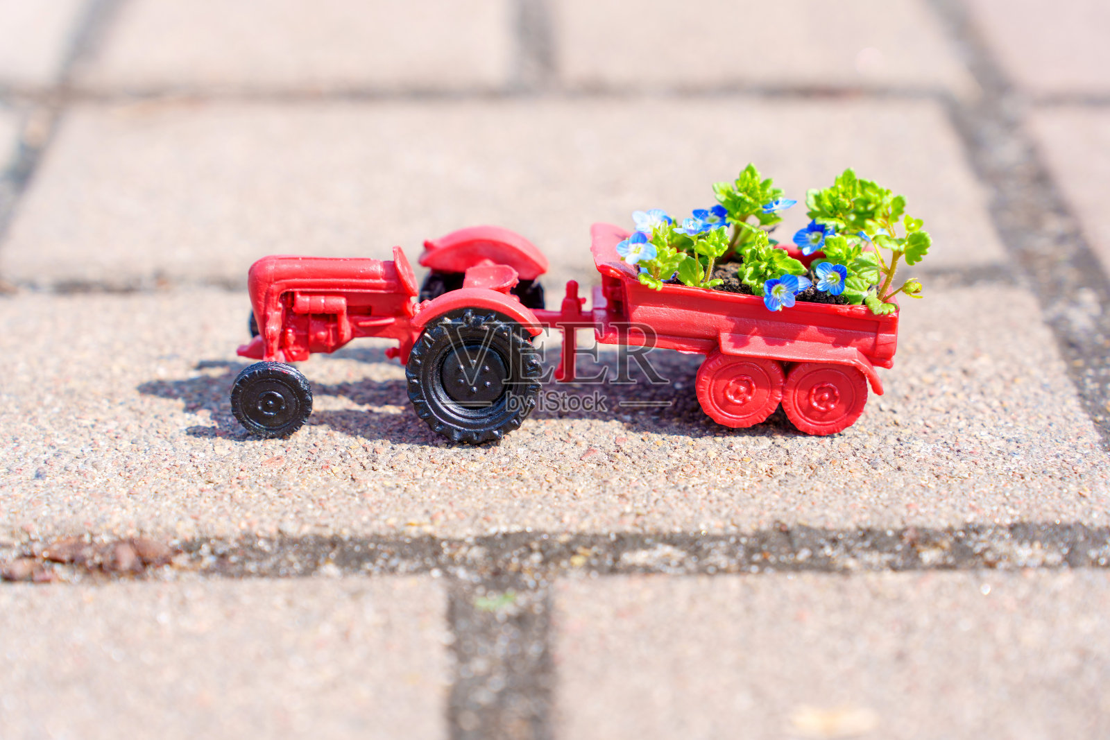 玩具拖拉机在人行道上搬运花坛照片摄影图片