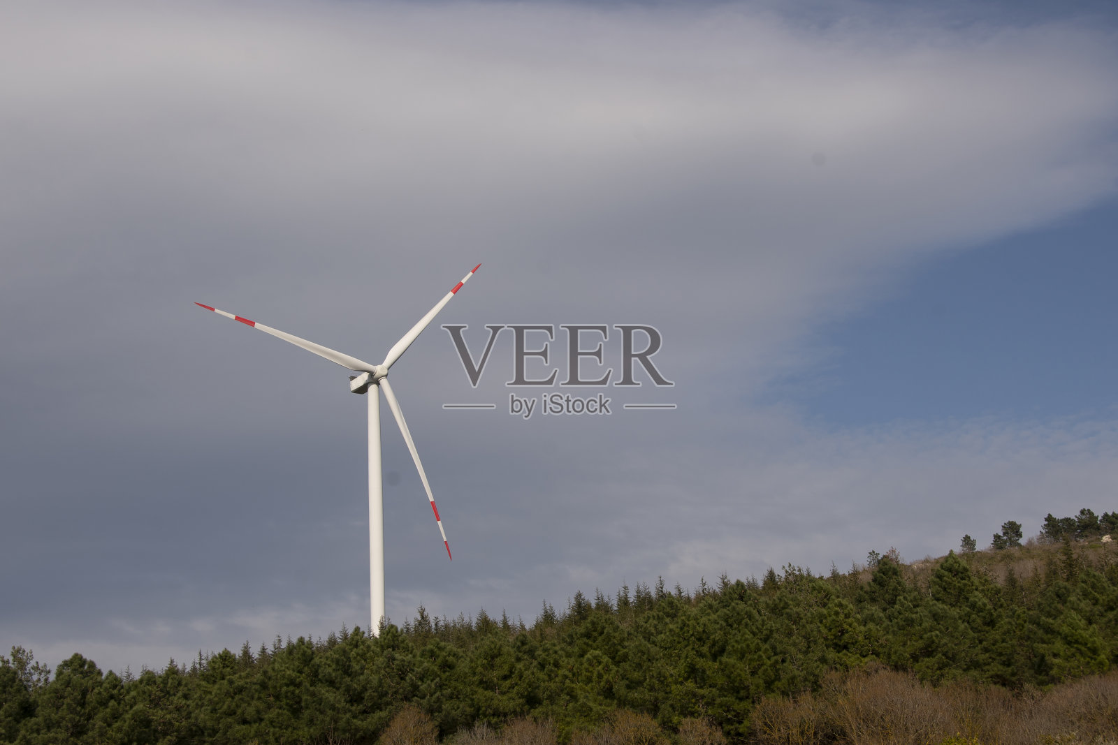 两台风力涡轮机在田地中央旋转发电。风力发电机和蓝天。照片摄影图片