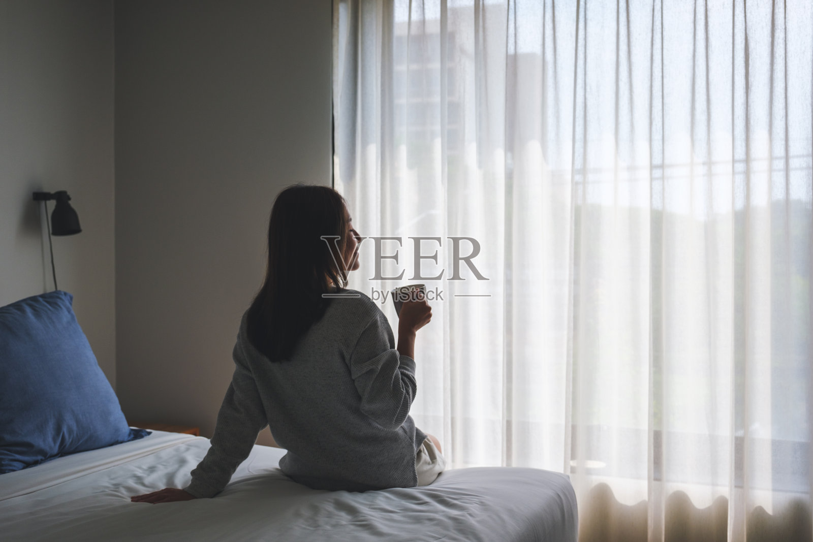 一名年轻女子在卧室醒来后喝热咖啡照片摄影图片