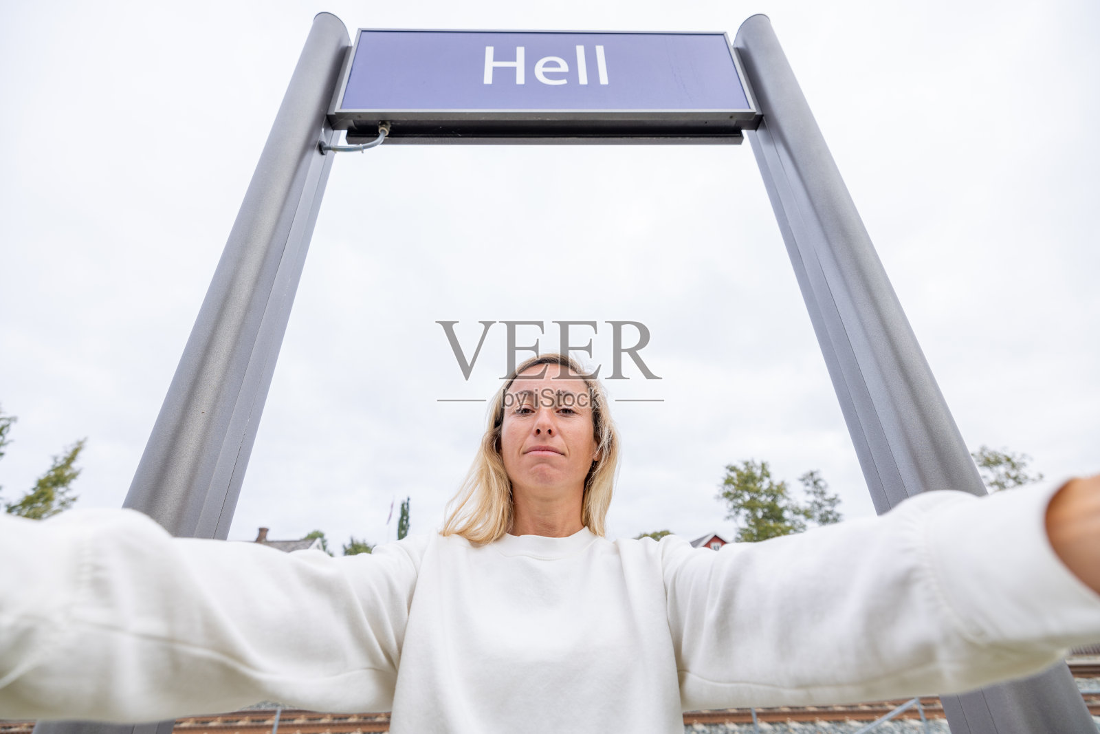 在挪威火车站地狱标志下做鬼脸自拍的女人照片摄影图片