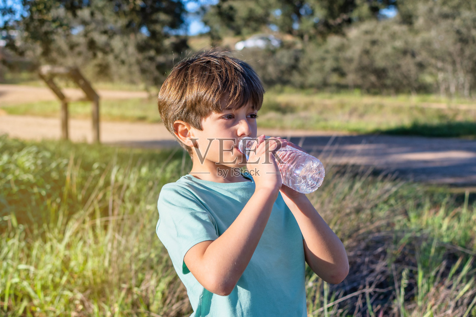 小男孩喝水降温。照片摄影图片