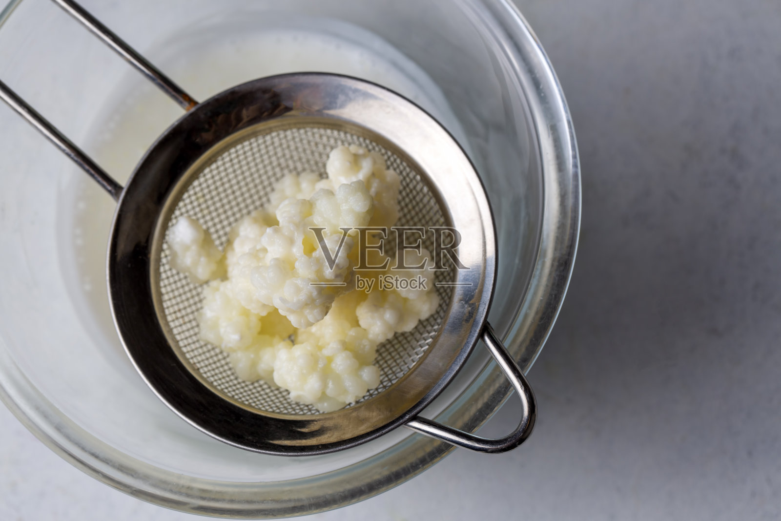 用克非尔谷物发酵的牛奶饮料。自制的开菲尔酒放在玻璃杯里，旁边是开菲尔谷物和牛奶照片摄影图片