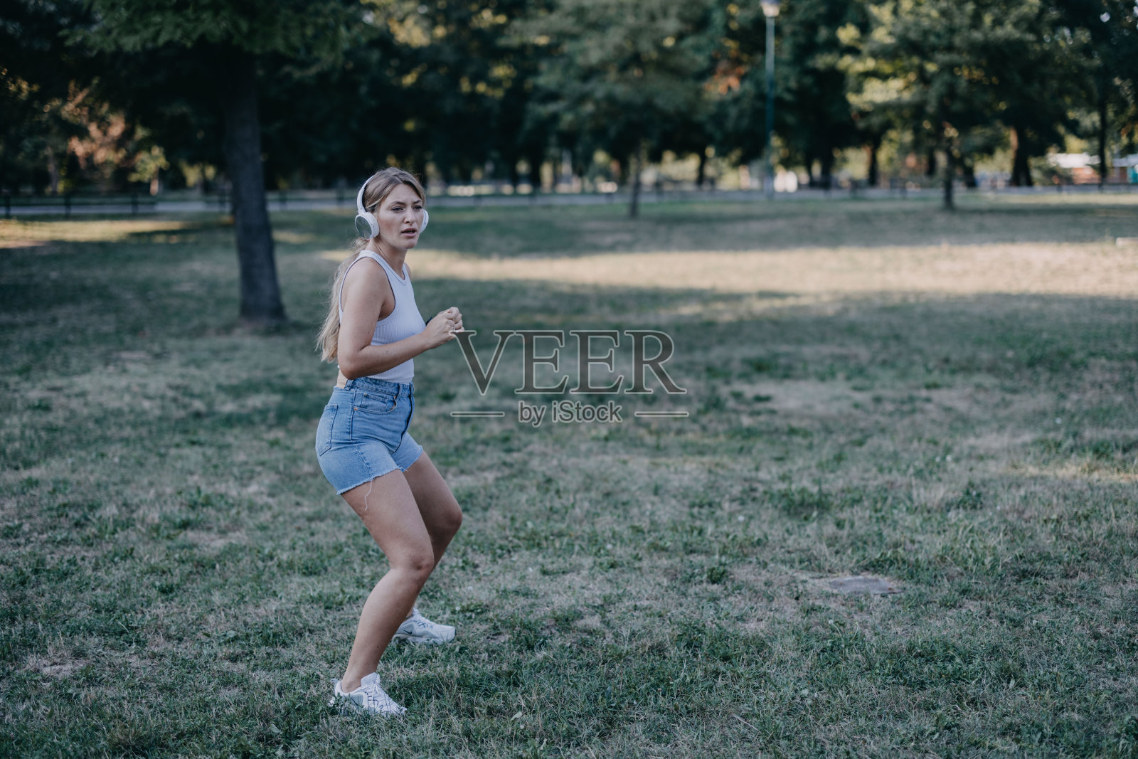 一名年轻女子边听音乐边伸展身体，准备在大自然中进行训练。照片摄影图片