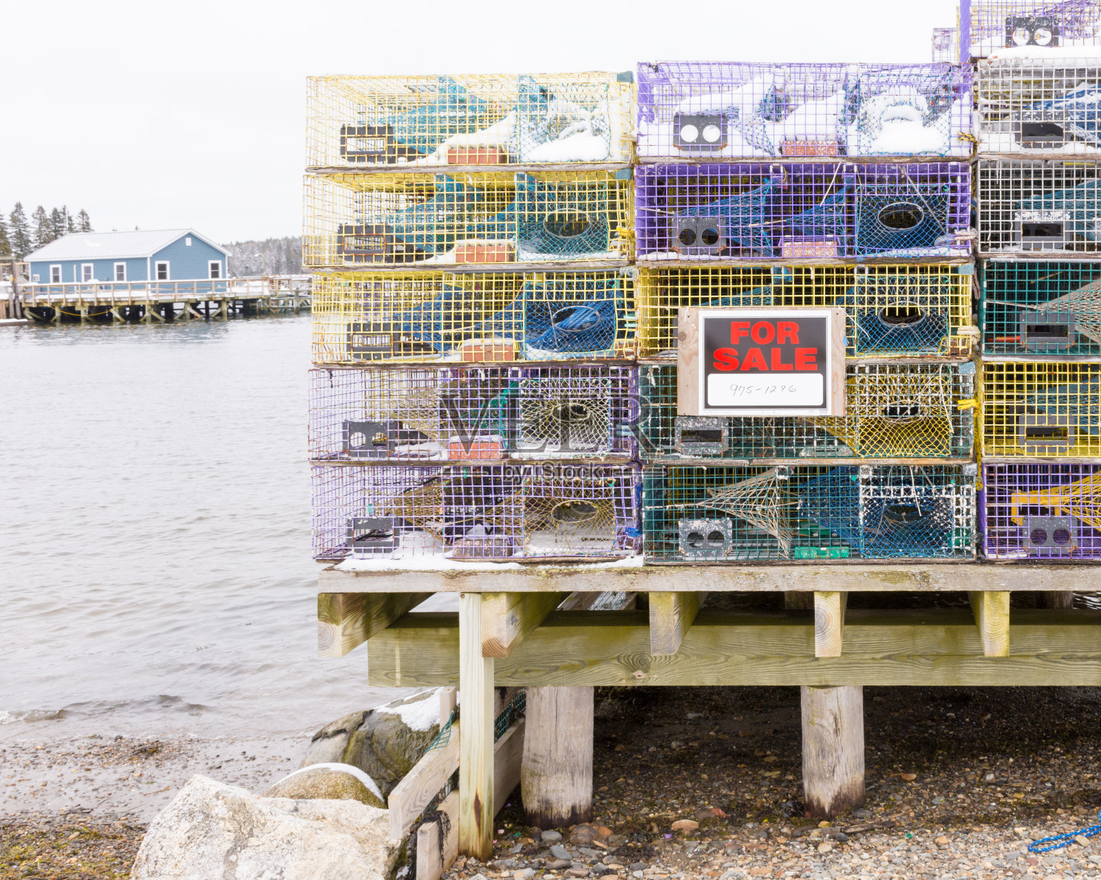 五彩缤纷的龙虾陷阱堆放在码头在冬季出售的标志，船屋和水。照片摄影图片