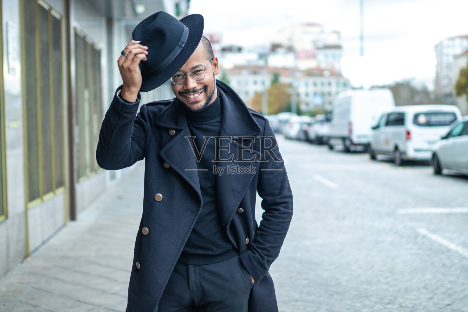 微笑的男人在街上挥舞着他的帽子照片摄影图片