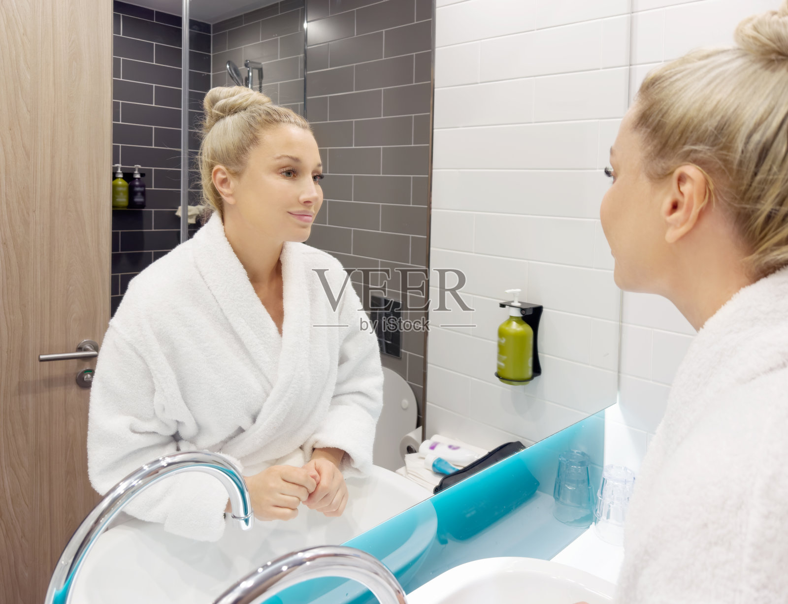 一个女人在浴室里照镜子，照顾她的皮肤。照片摄影图片